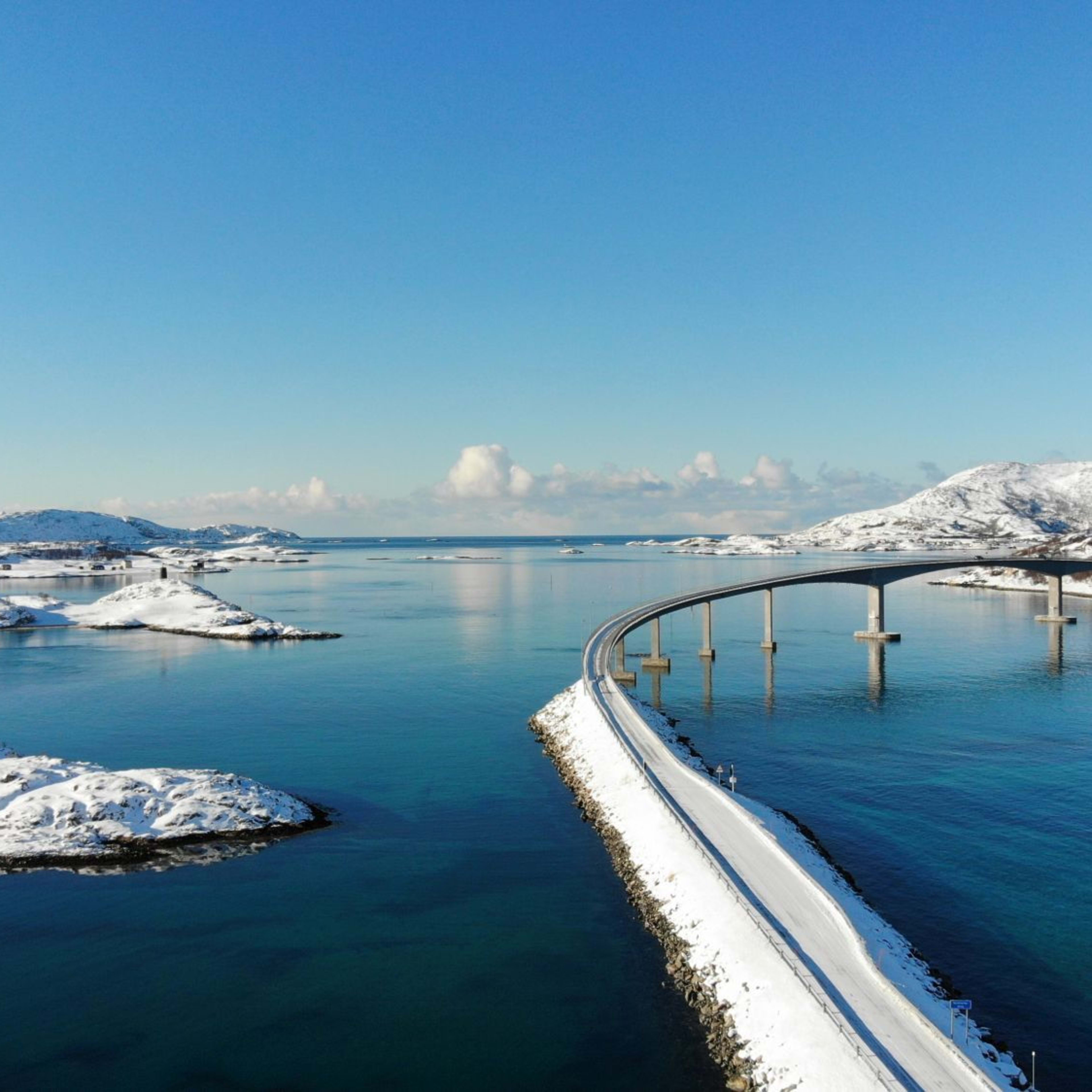 Arktische Küstenlandschaft in Tromsø mit schneebedeckten Bergen, klarem Fjordwasser und verstreuten Inseln