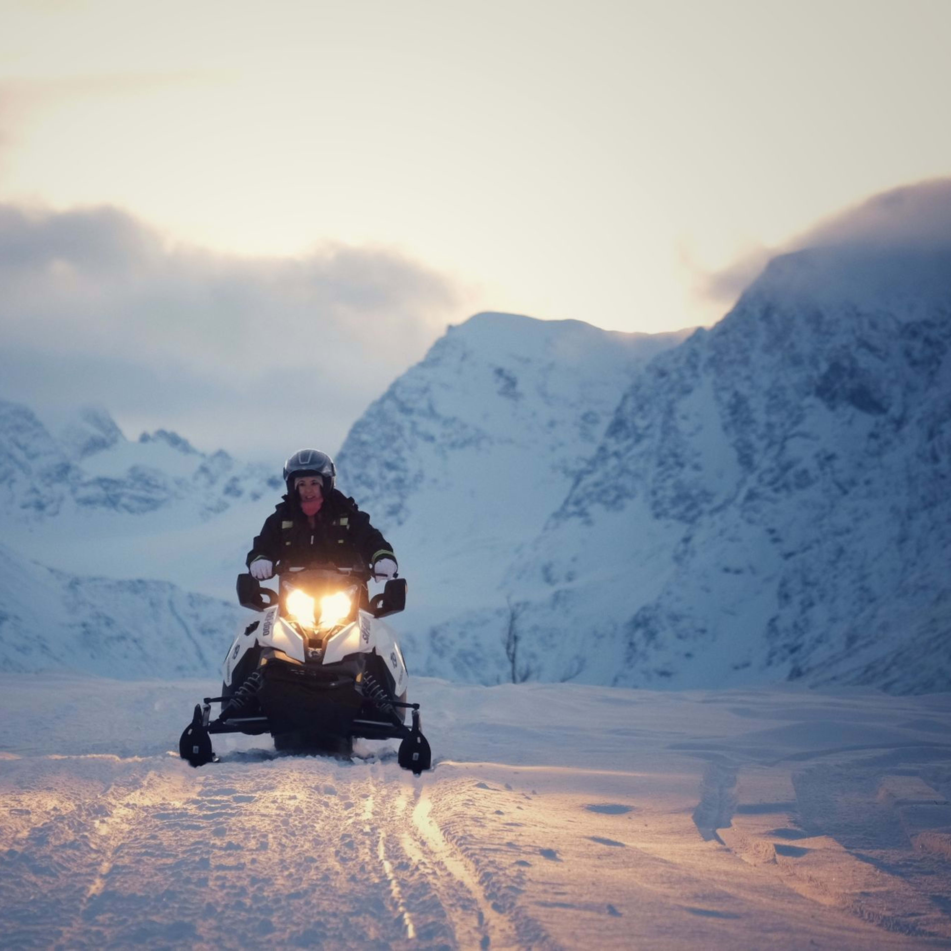 Snowmobile adventure in Lyngen Alps at sunset with pink sky and snow-covered mountains near Troms