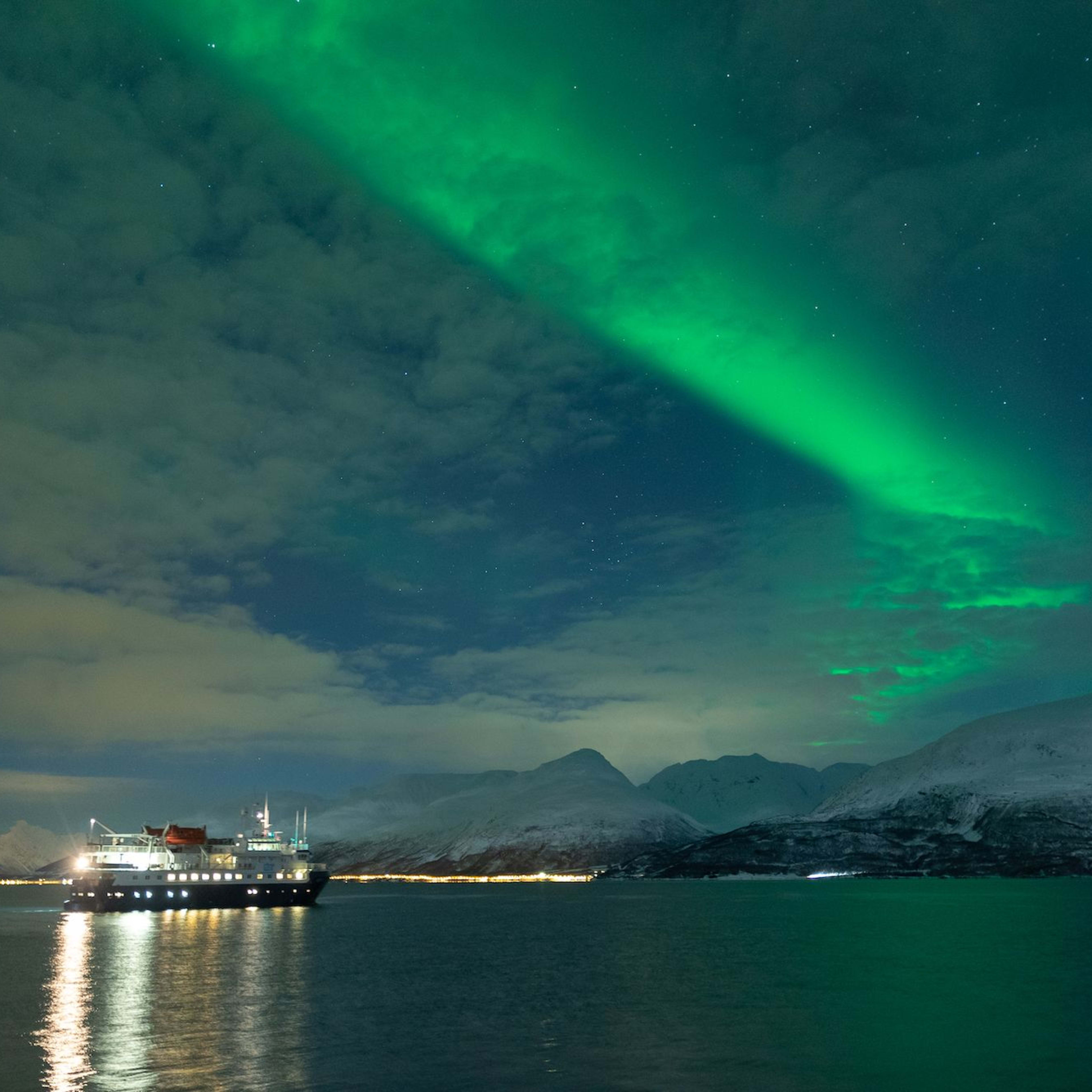 Et skip under nordlyset, flytende på rolige arktiske farvann.
