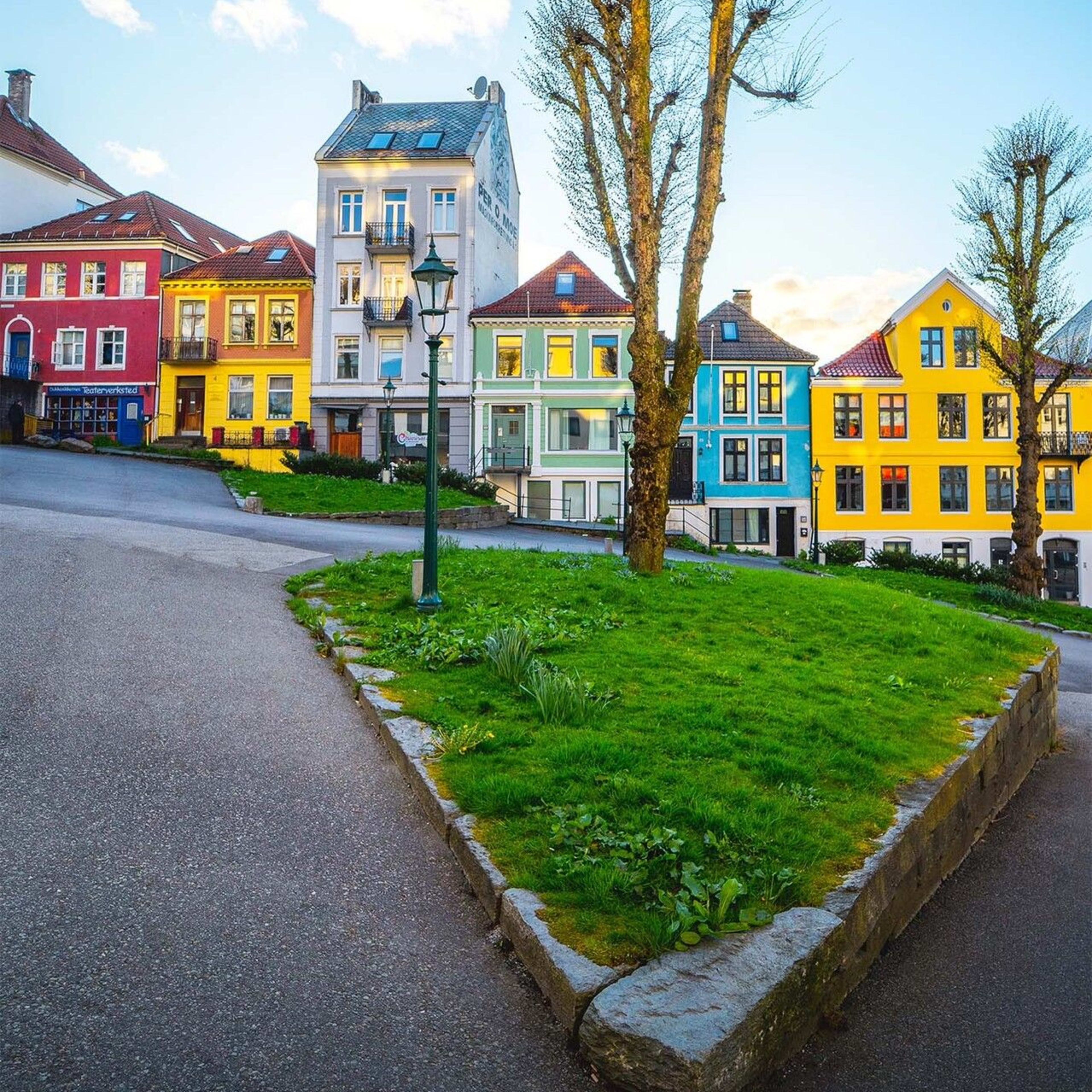 Bunte Holzhäuser säumen eine Kopfsteinpflasterstraße in Bergen, Norwegen an einem sonnigen Tag