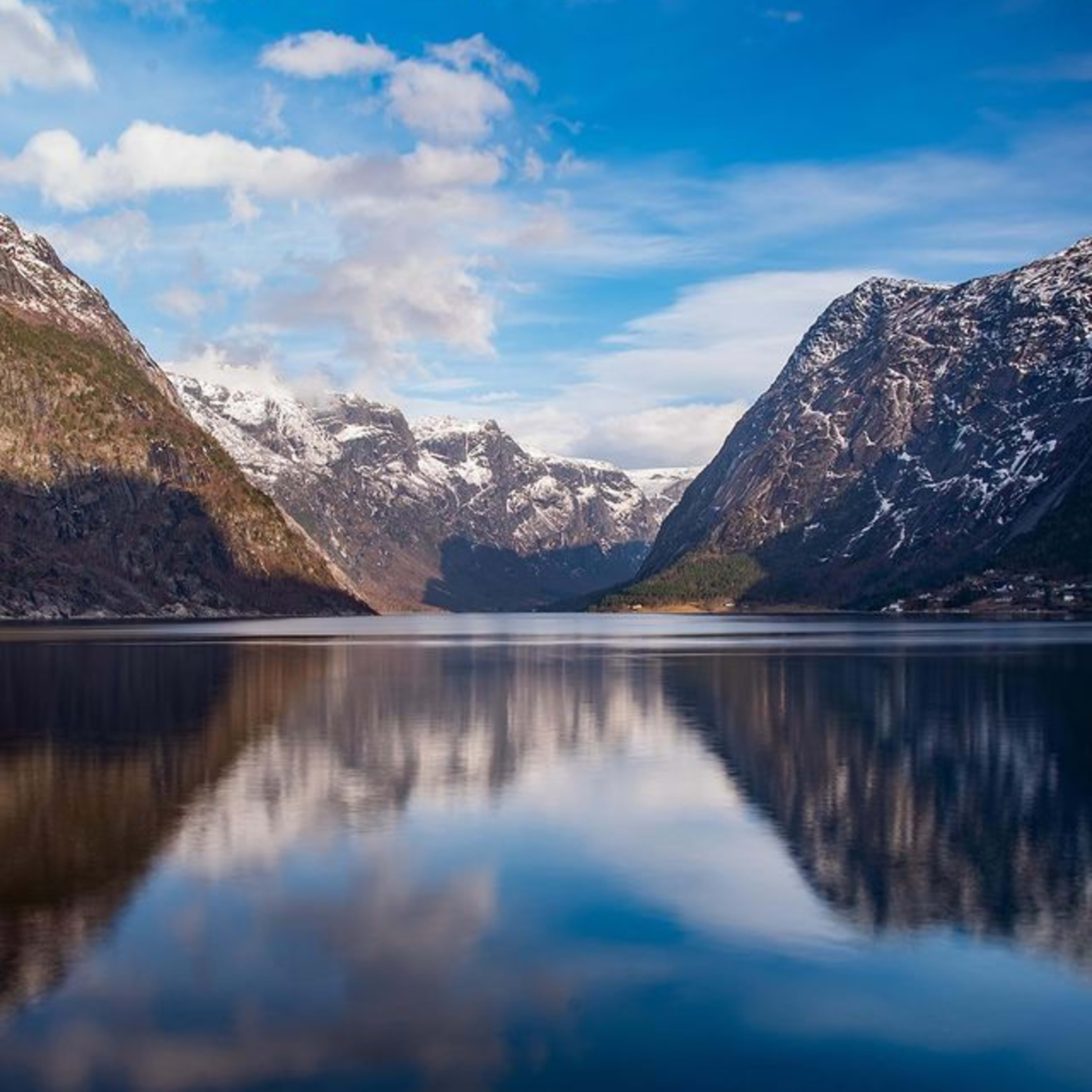 Fjord mit schneebedeckten Bergen im blauen Wasser.