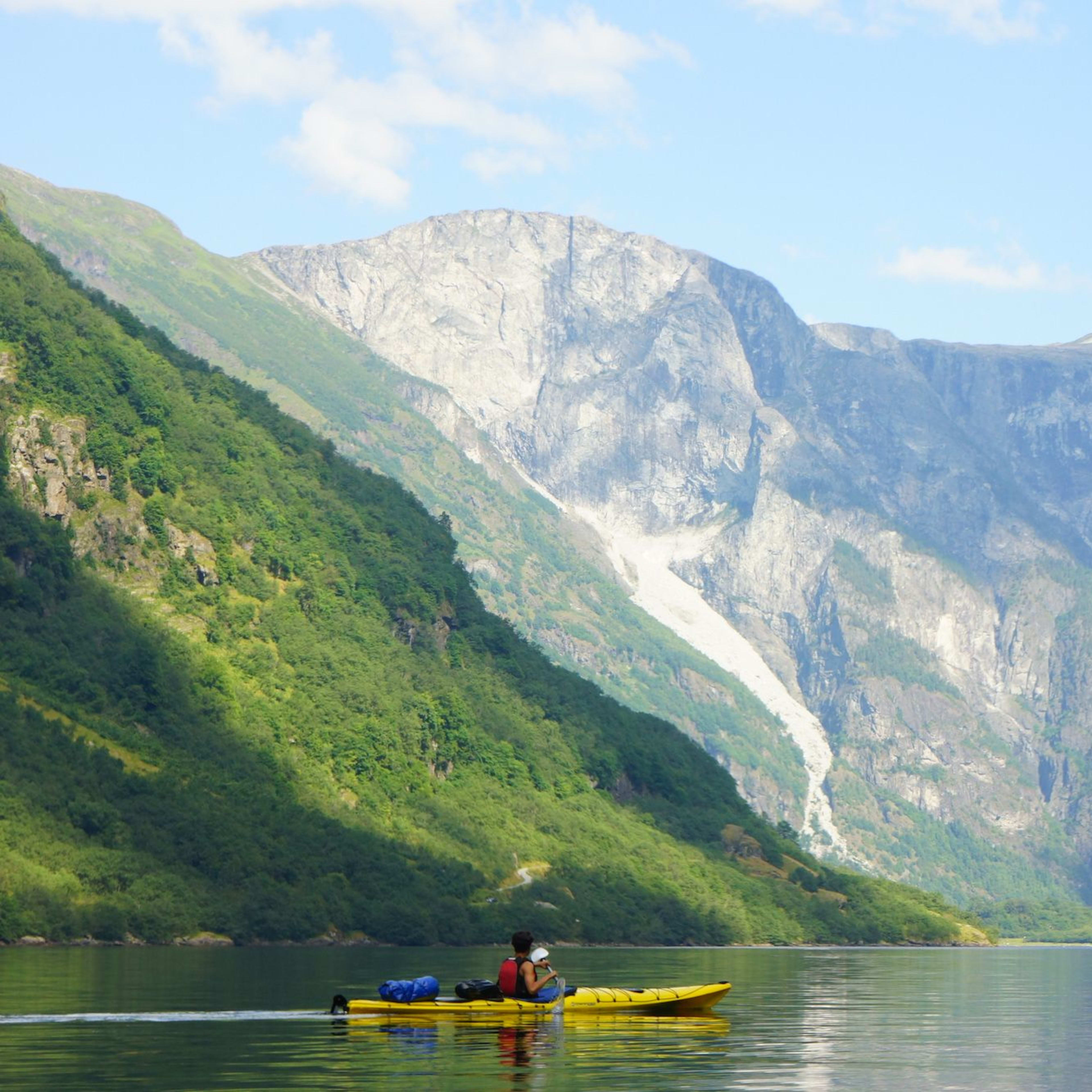 Kajakkpadler på UNESCO-listede Nærøyfjorden i Gudvangen omgitt av bratte fjell og norsk verdensarvfjordlandskap