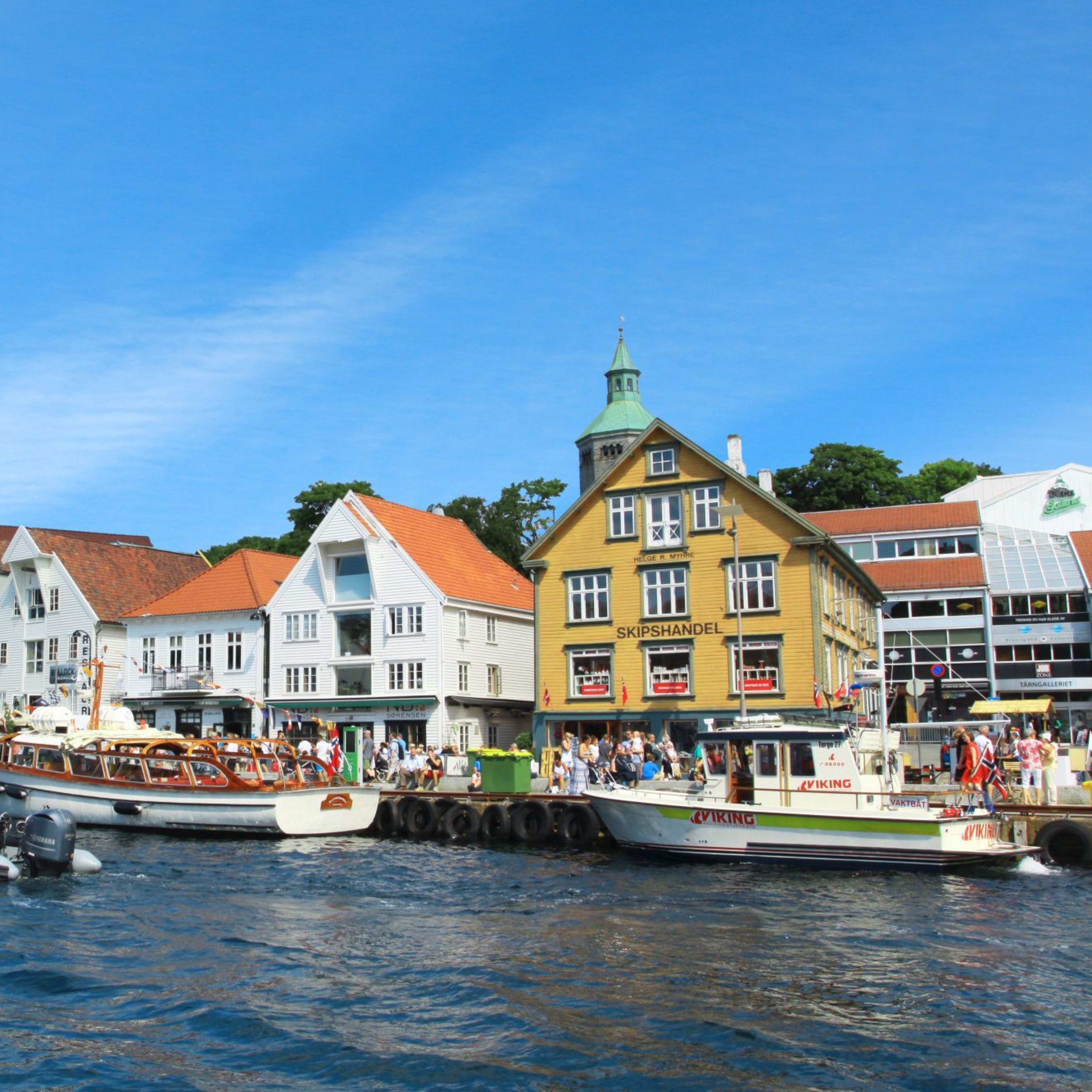 Havn med fargerike bygninger og båter i sommersol.