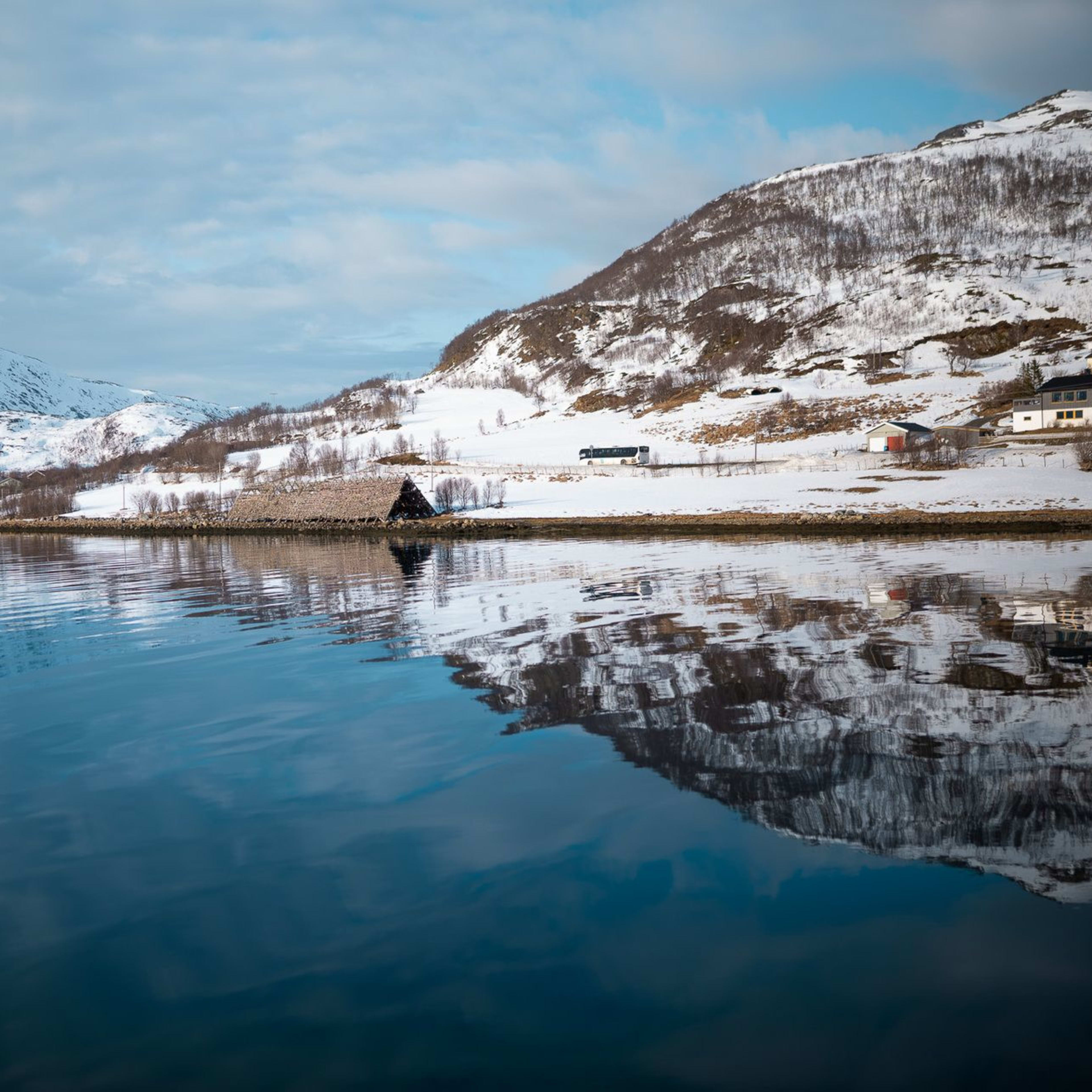Arctic landscape in Tromsø with calm water reflecting snow-covered mountains