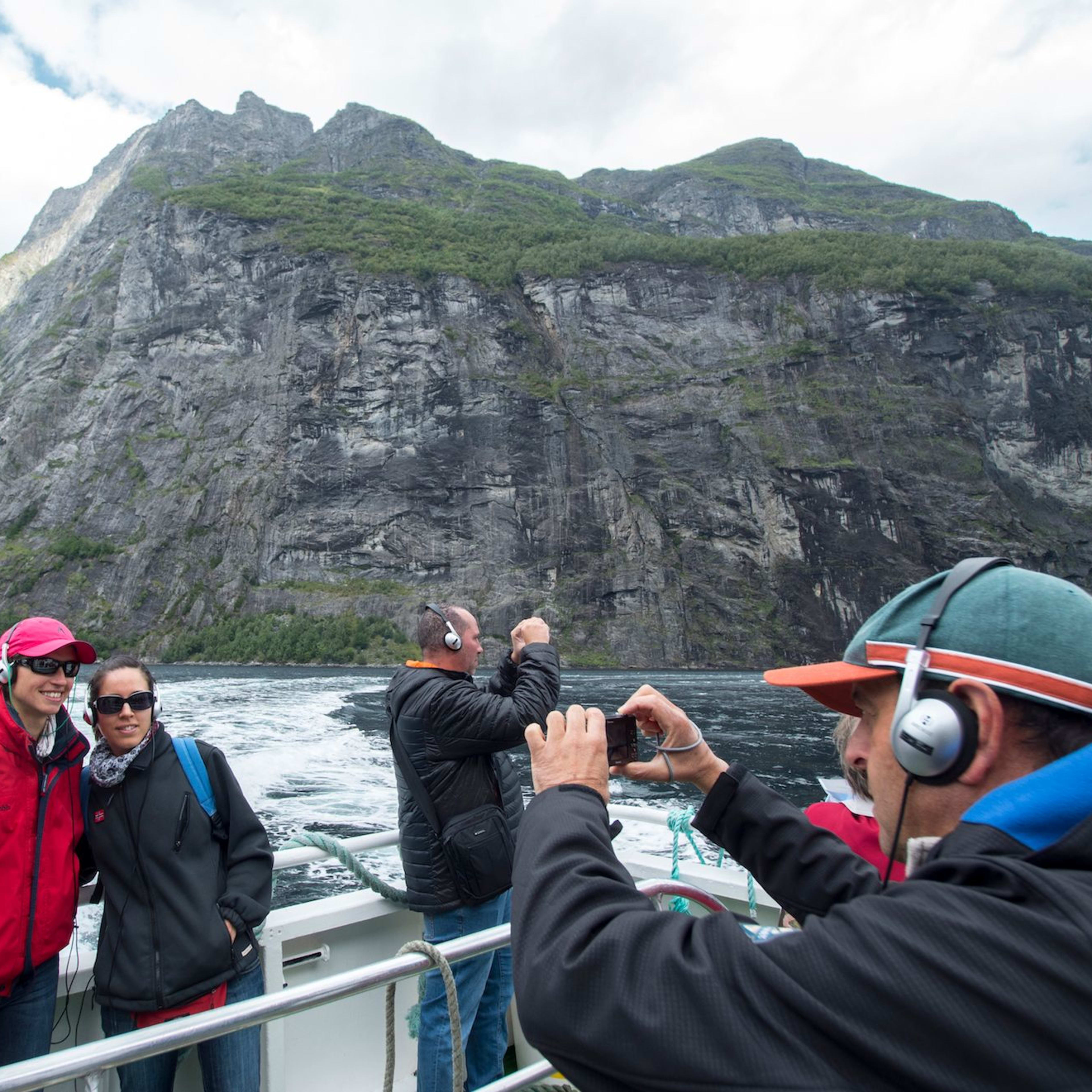 Touristen auf der Sightseeing-Tour im Geirangerfjord machen Fotos von der wunderschönen Fjordlandschaft.