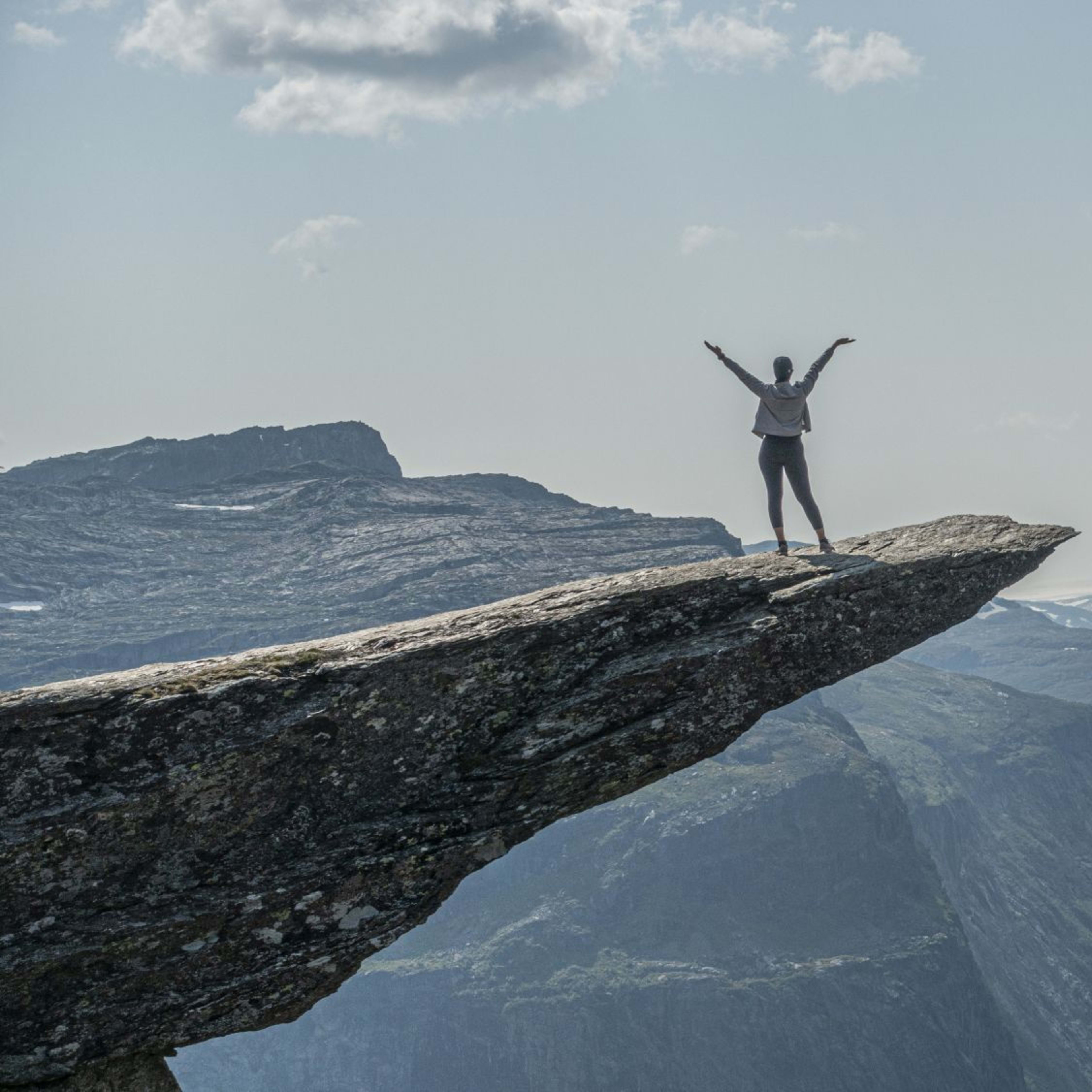 Happy girl at the tip of Trolltunga after hiking the classic route to Trolltunga