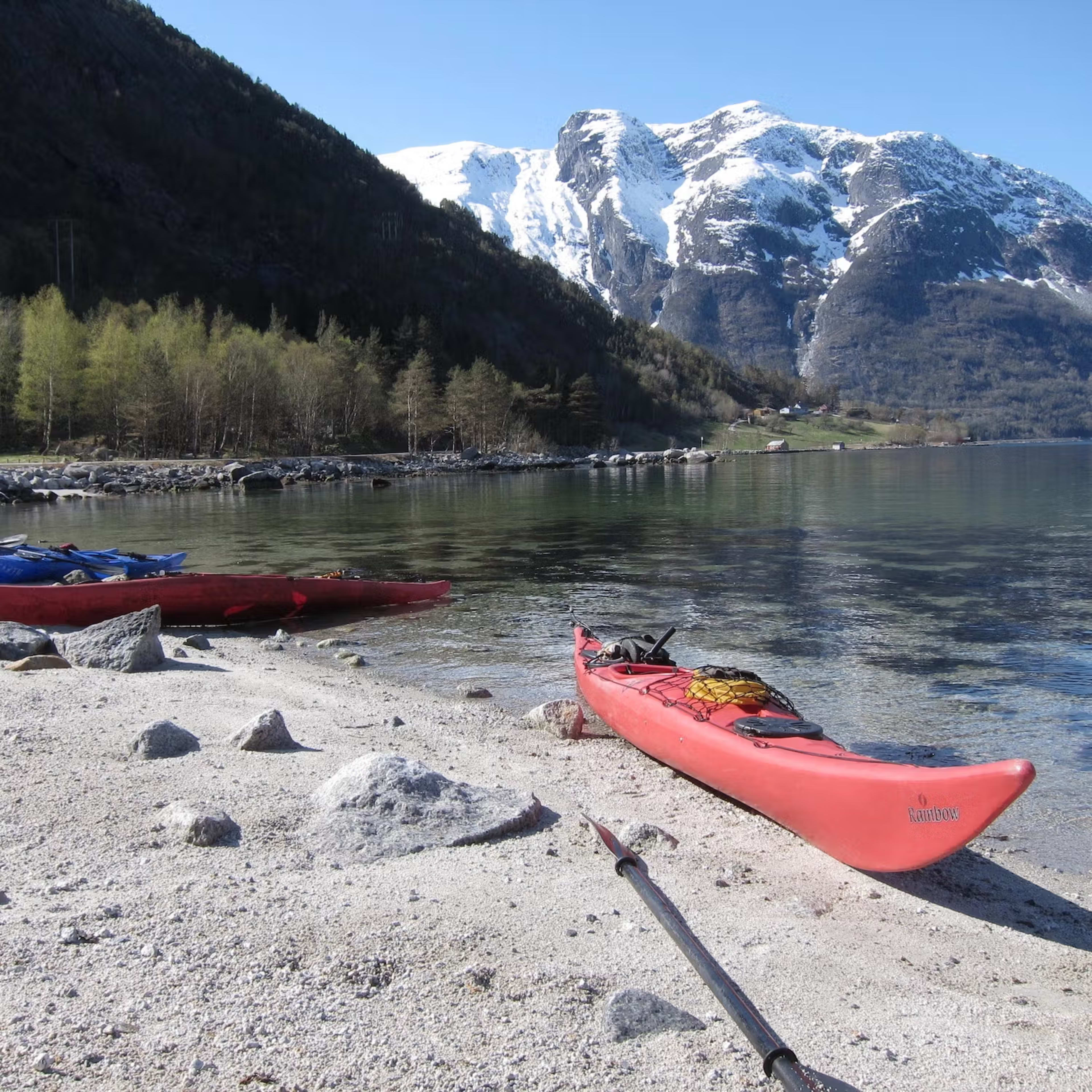 Rote und blaue Kajaks am Felsstrand während Eidfjord Kajaktour