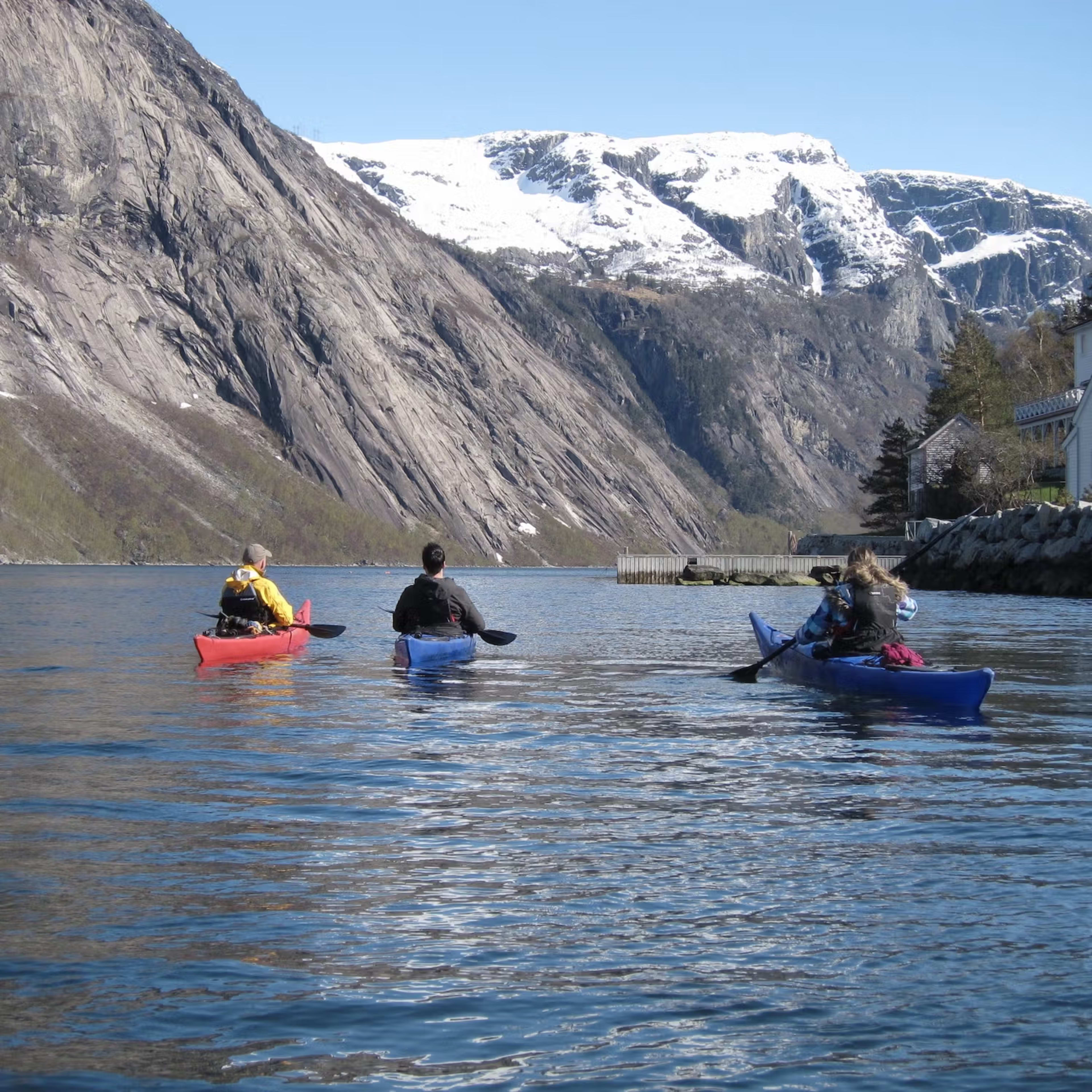Kajakgruppe genießt Frühlings-Paddeln auf Hardangerfjord mit schneebedeckten Bergen