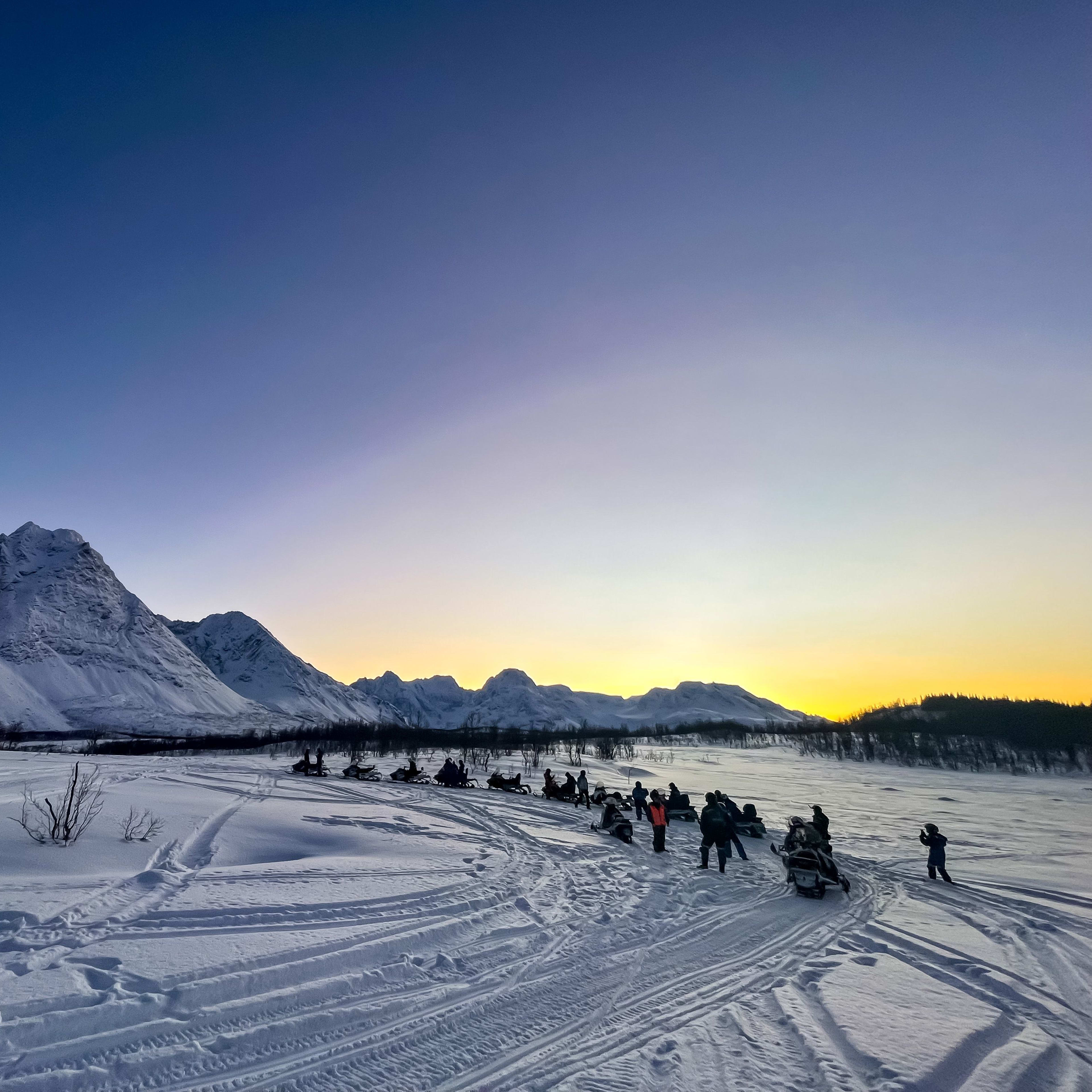 Populær snøscooter-tur samling i naturskjønn dal med majestetiske fjelltopper rundt.