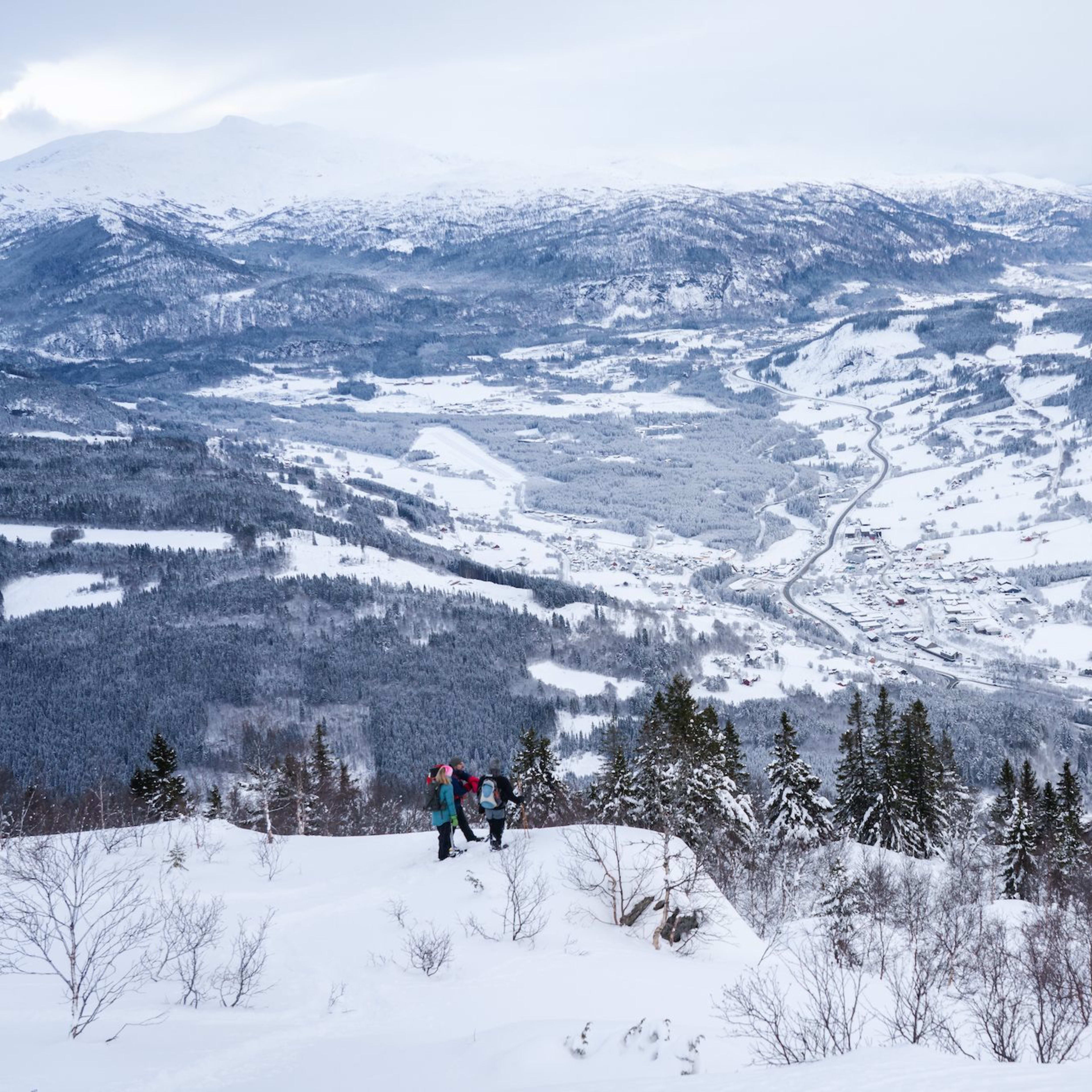Drei wandern im Tiefschnee über Tal.