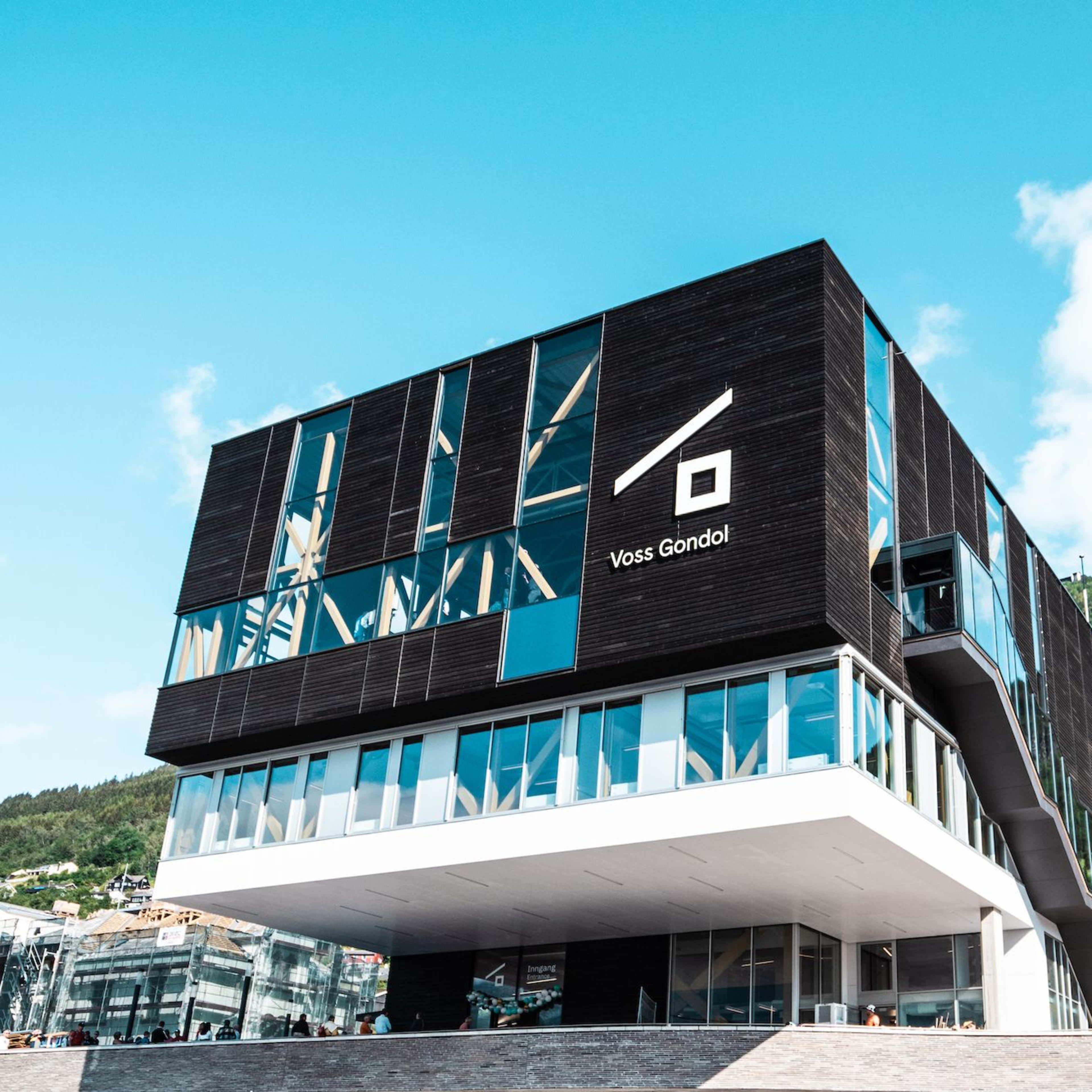 Voss Gondol terminal in Voss with black-white modern design, logo visible, gondola line rising into forest.