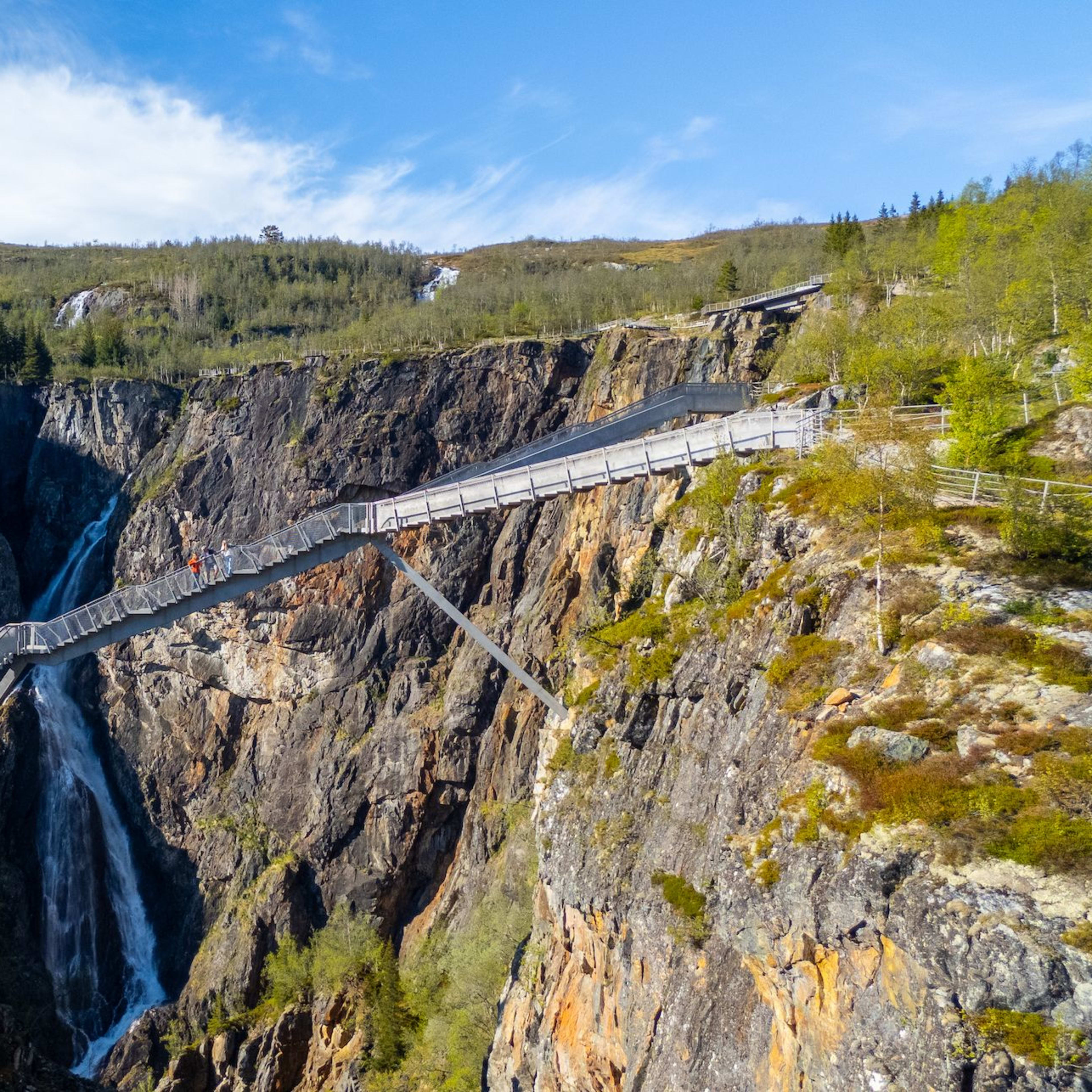 Trebro som spenner over den kraftige Vøringsfossen med besøkende som går over fossenedenfor