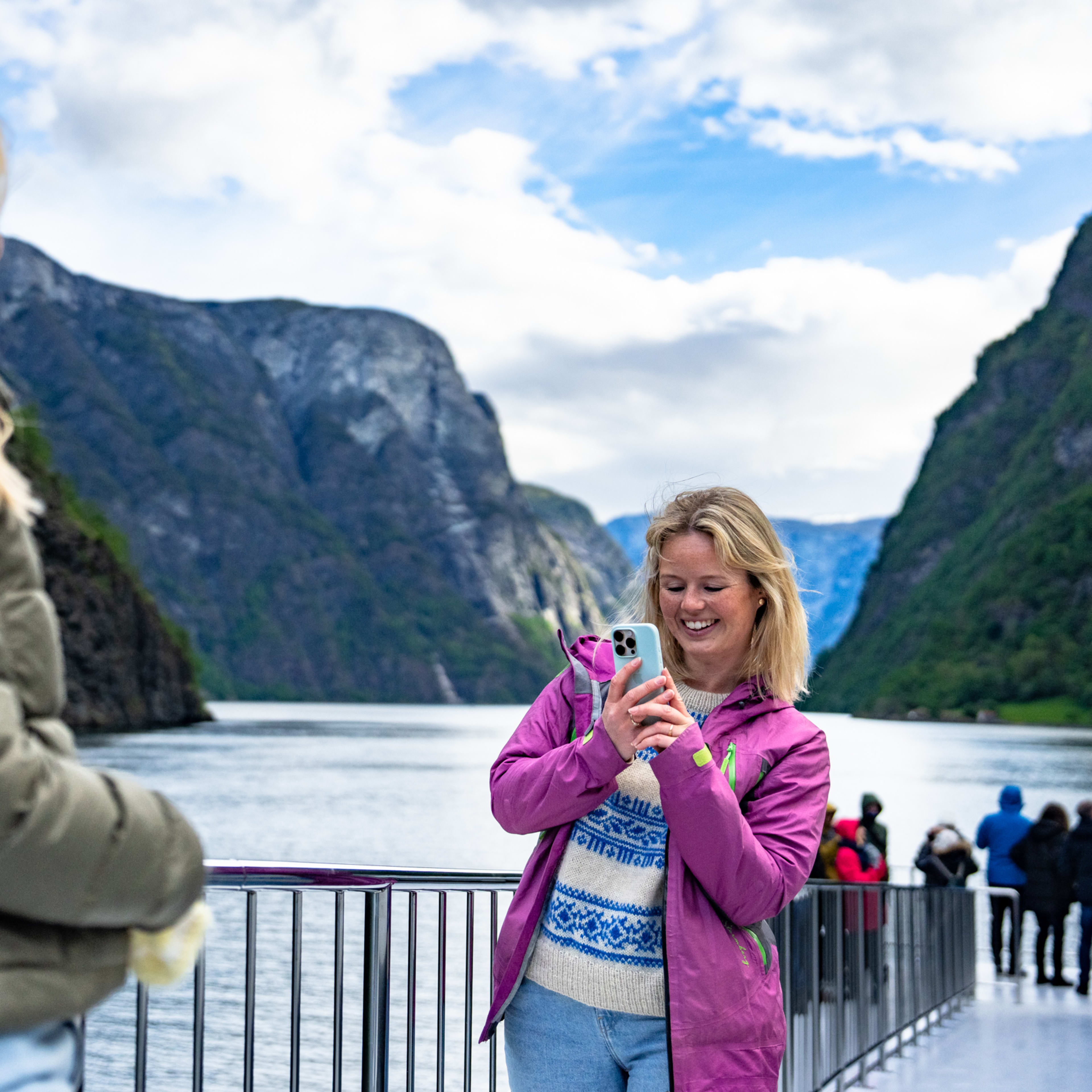 To kvinner nyter utsikten fra dekk på fjordcruise mellom Flåm og Gudvangen gjennom UNESCO-listede Nærøyfjorden