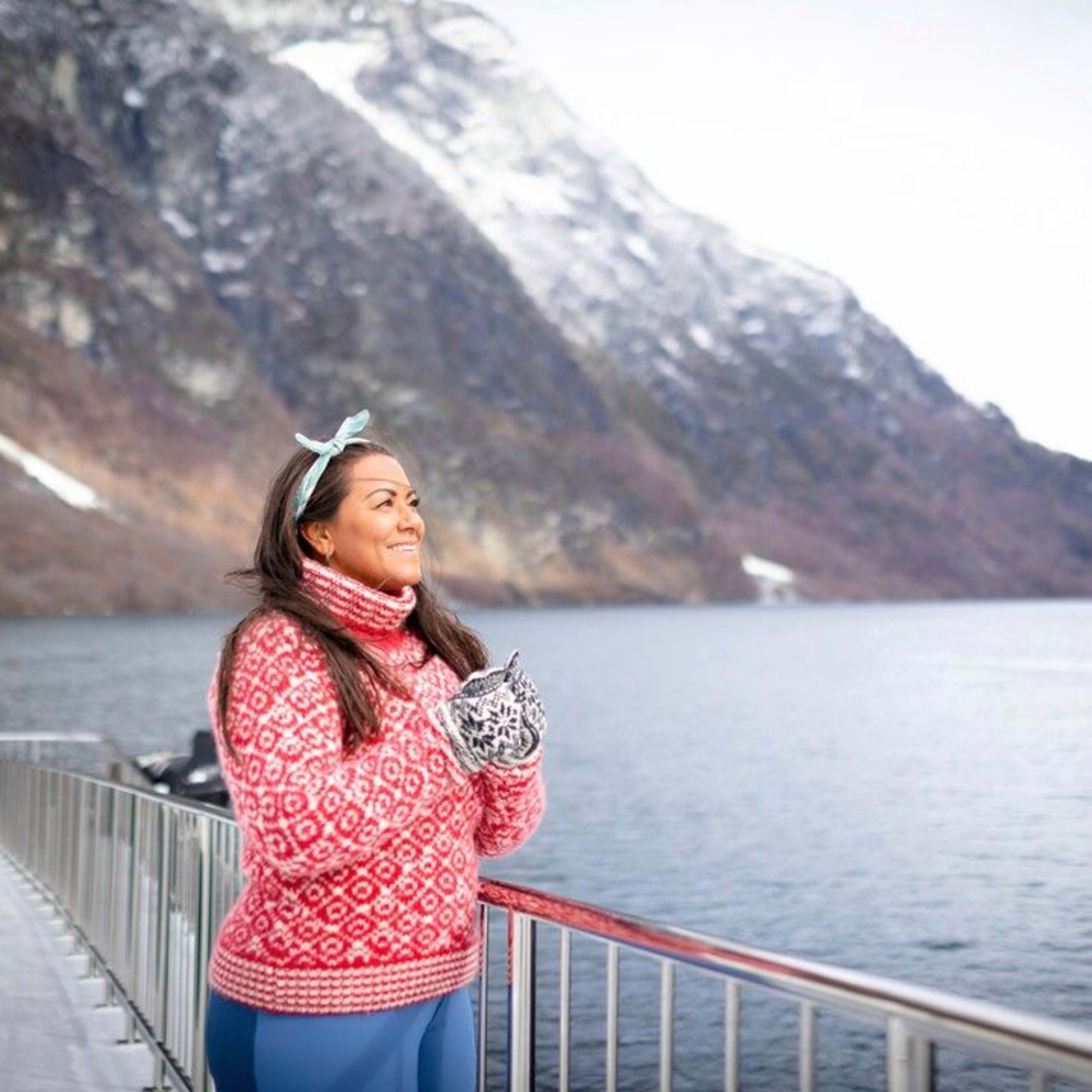 Kvinne på deck på fjordcruiset på Nærøyfjorden, omgitt av snødekte Nærøyfjord og fjell.