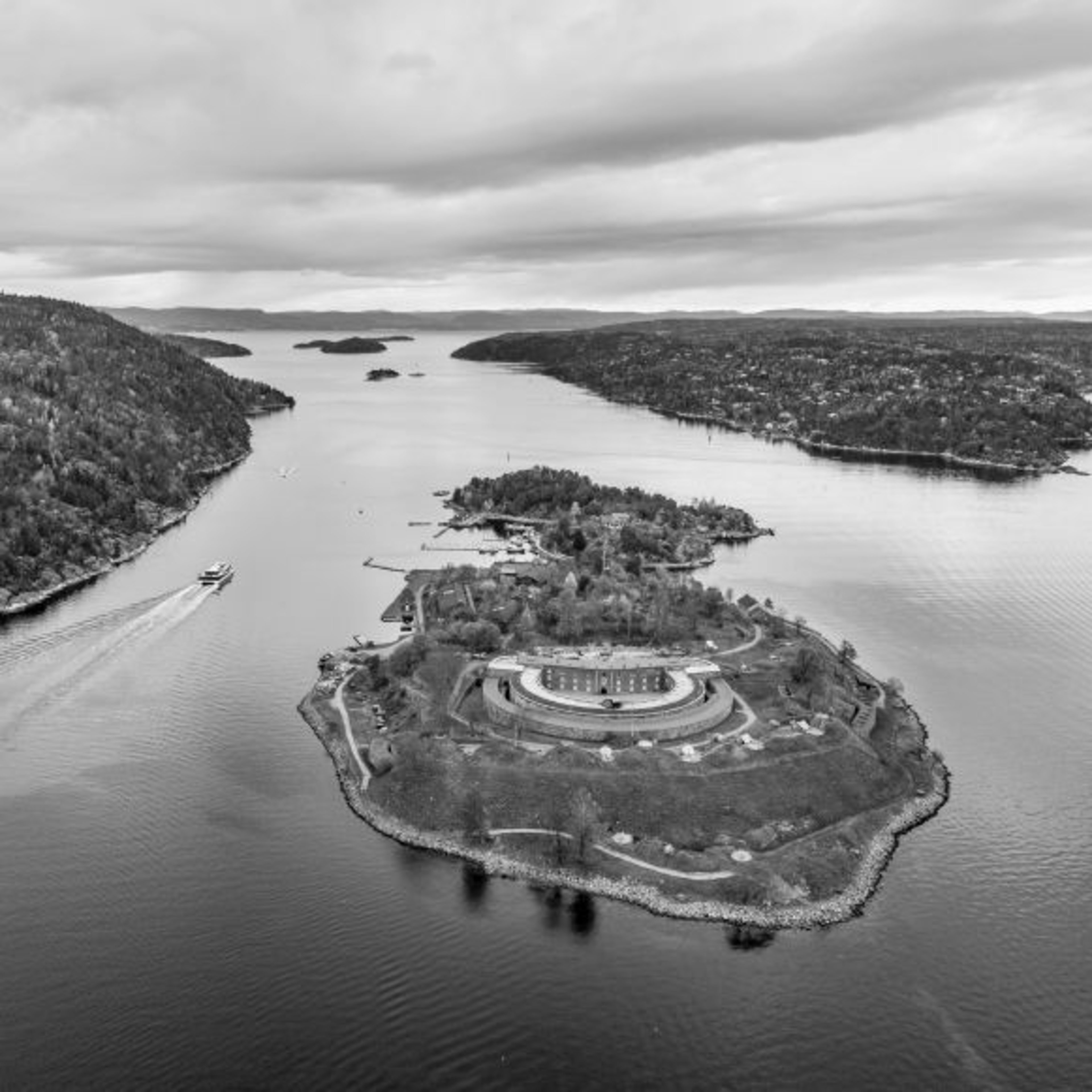 Aerial view of islands and ferry in peaceful waterway, with round structure on lush island.