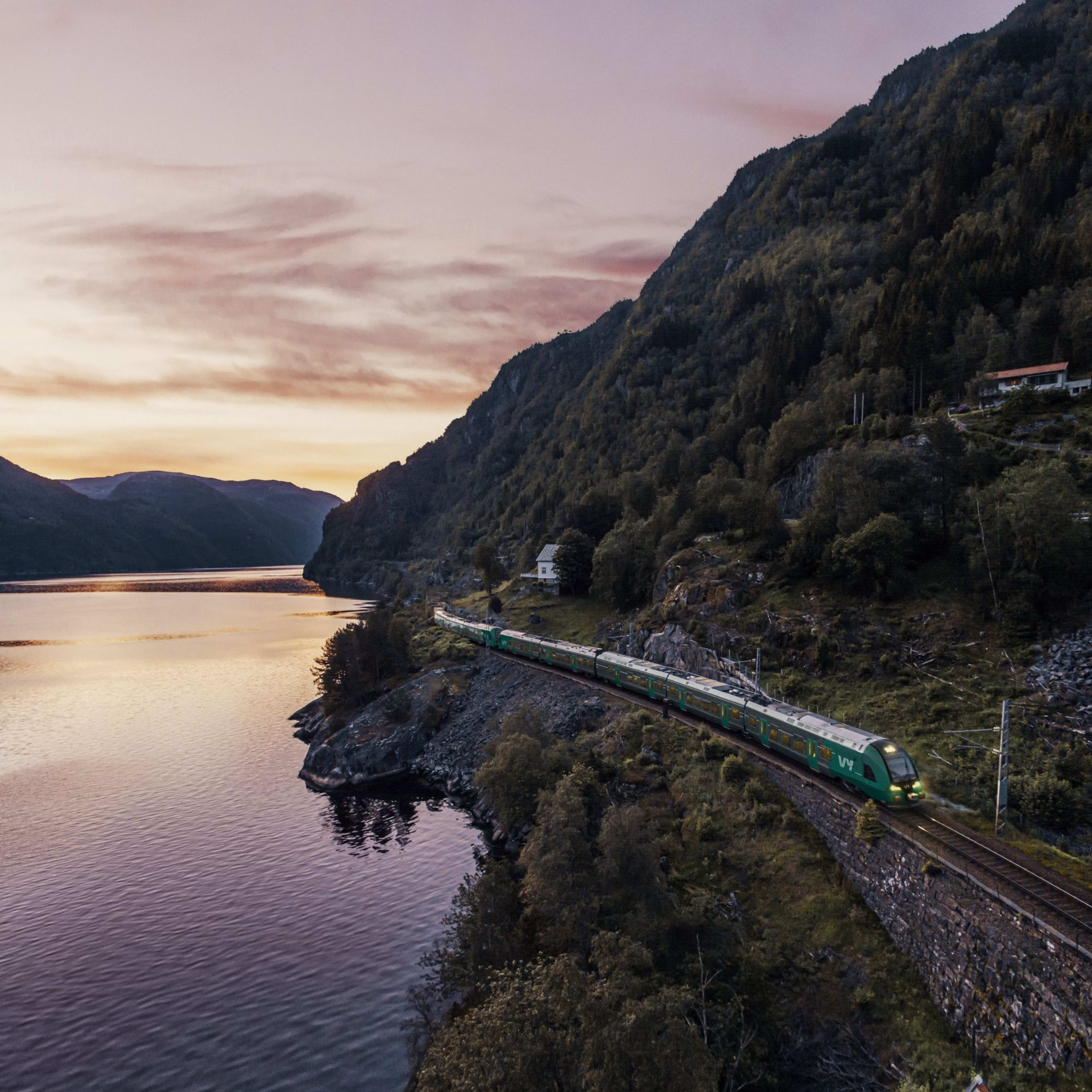 The Bergen railway rides hillside at sunset, sky glowing orange and purple.