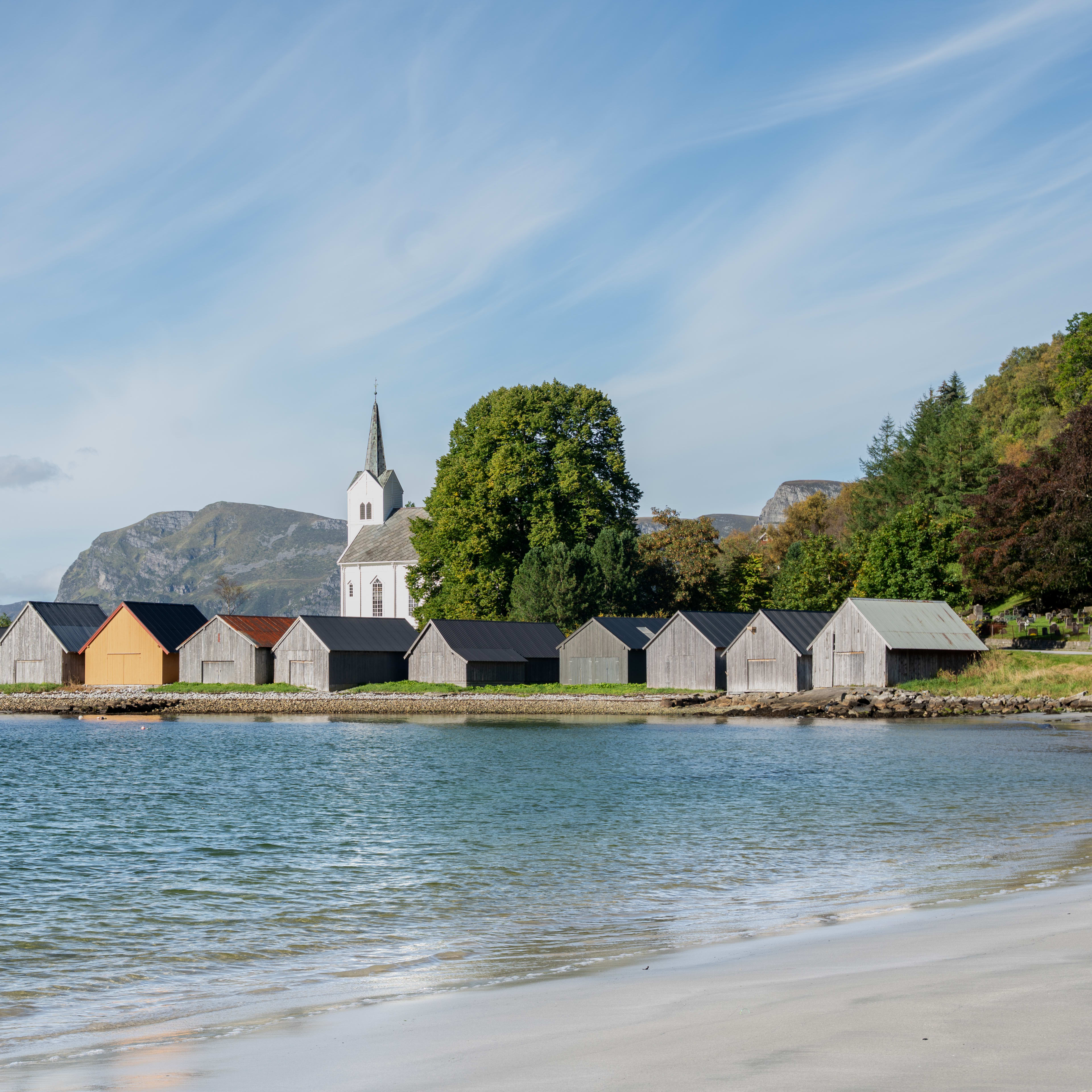 Selje Church on Stadlandet, with wooden boathouses along the shore