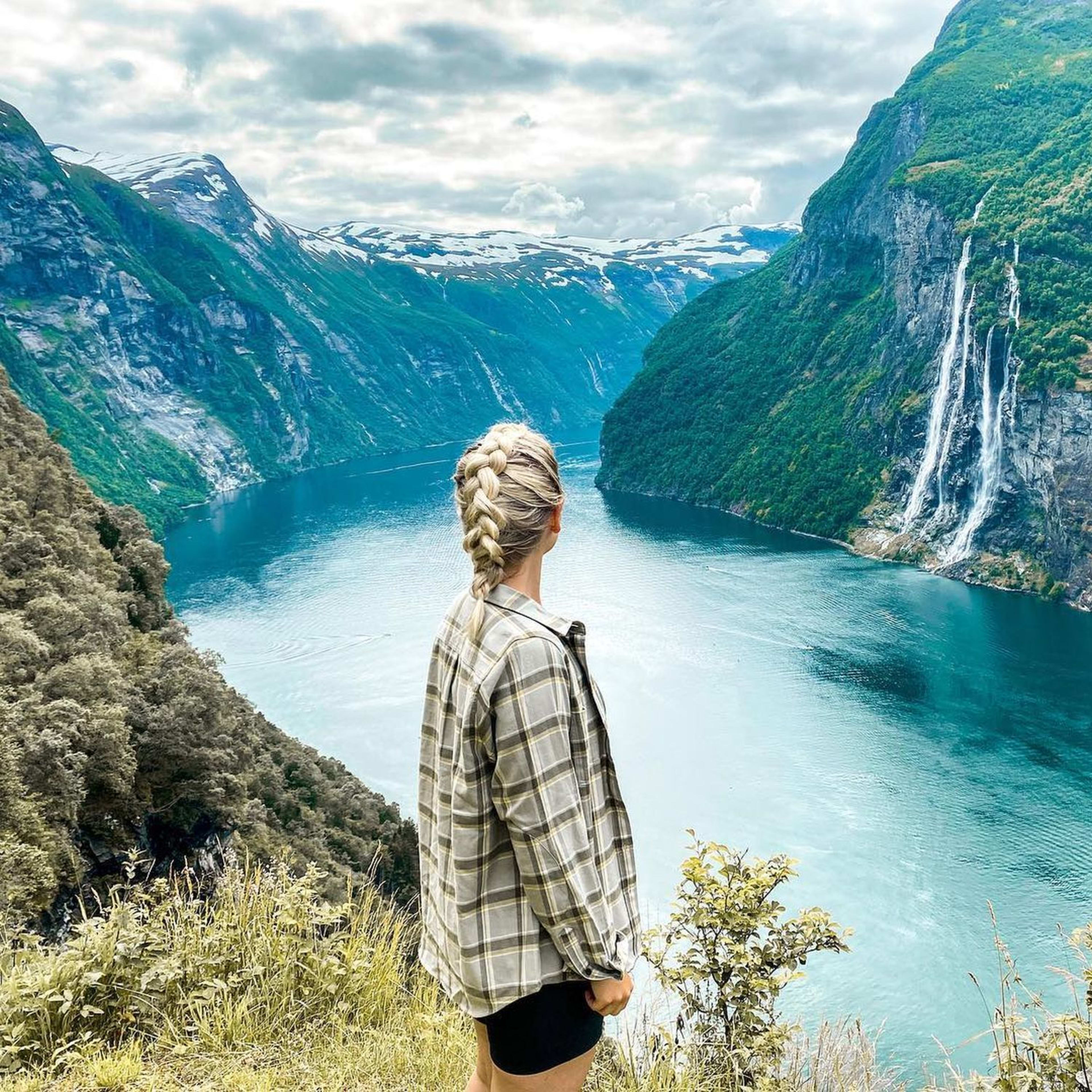 Kvinne på fjellgården Skageflå skuer utover Geirangerfjorden og fossene.
