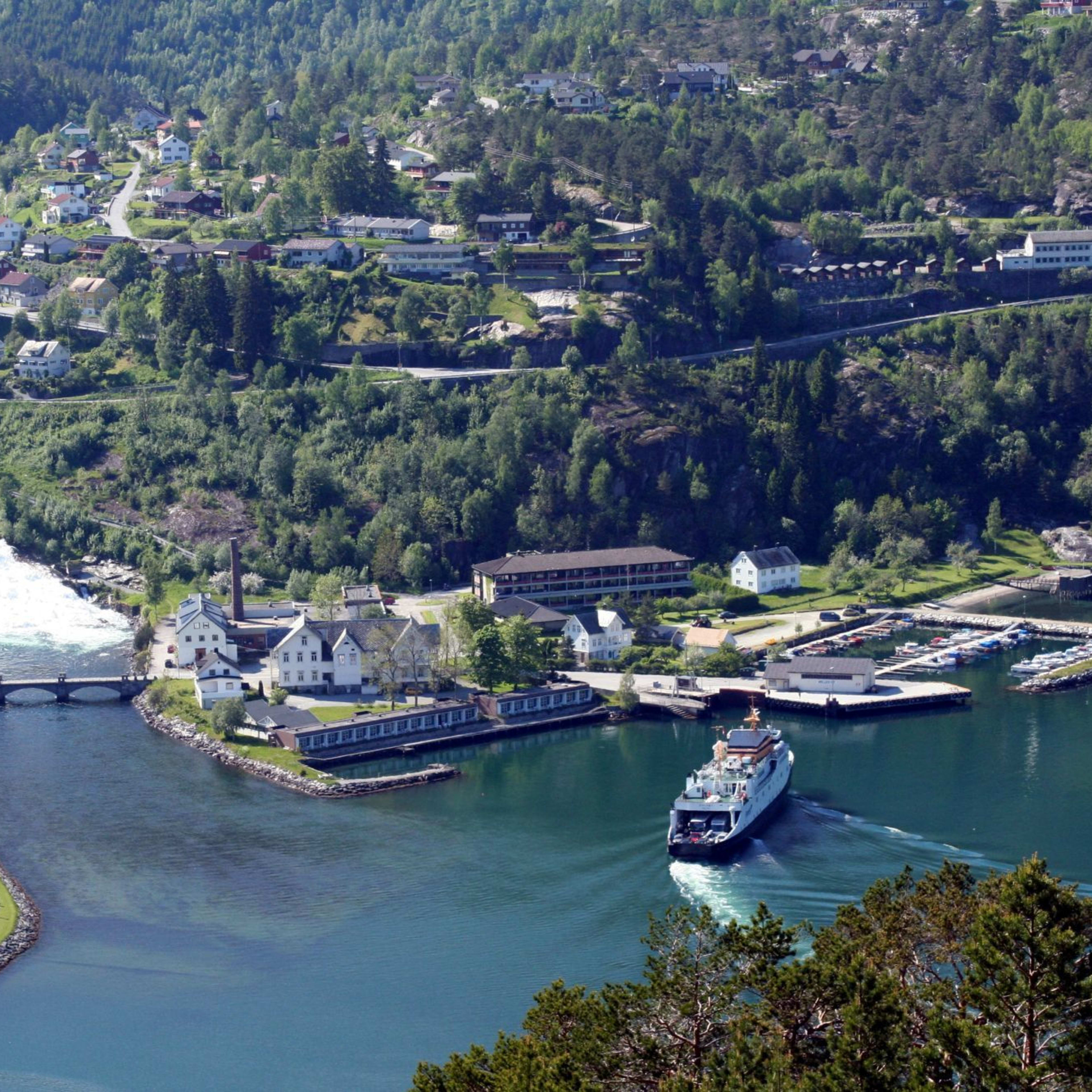 Luftaufnahme von Dorf, Fähre, Hafen und Wasserfall.