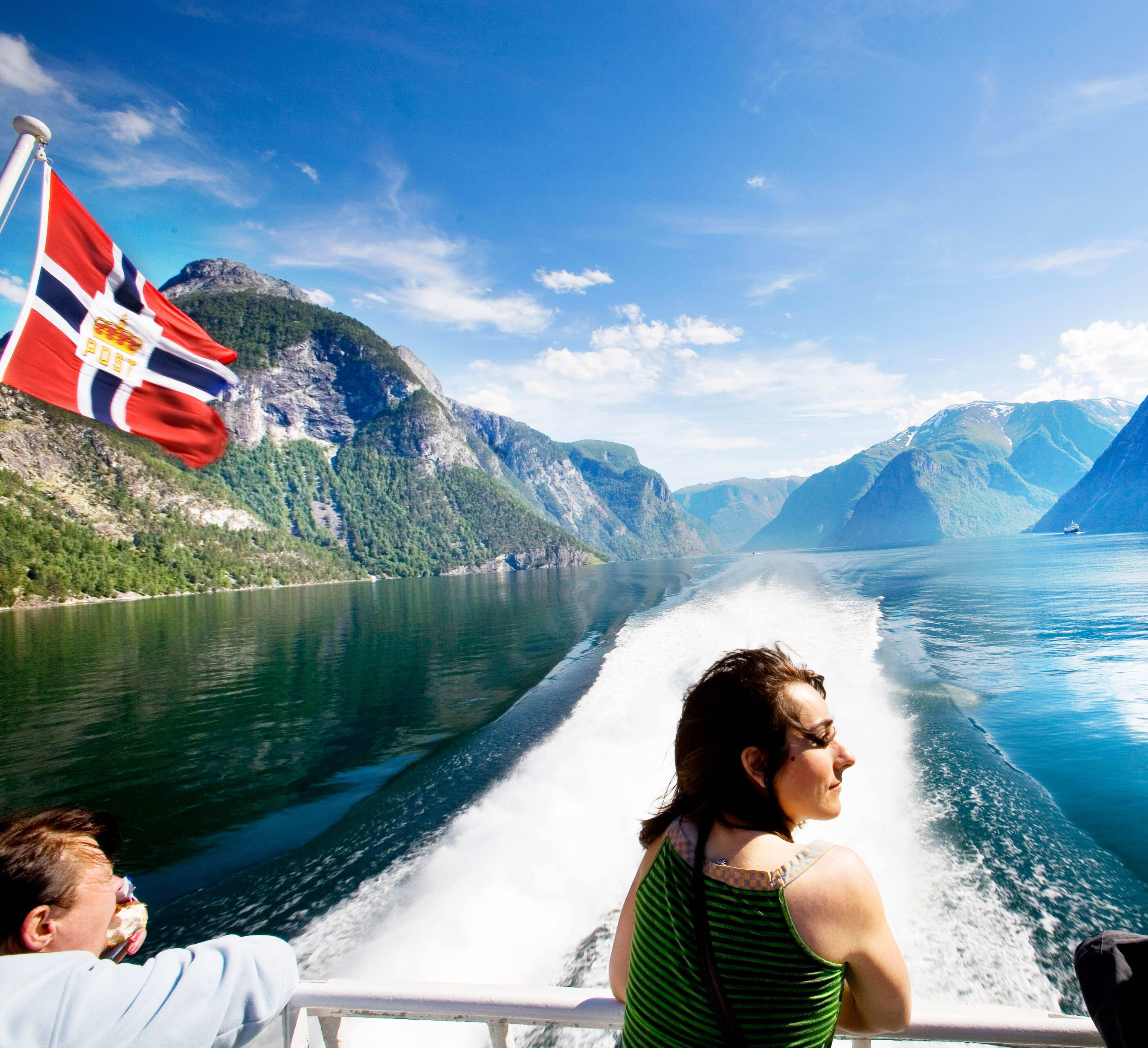 Boot am Sognefjord mit wehender Flagge und Kielwasser.