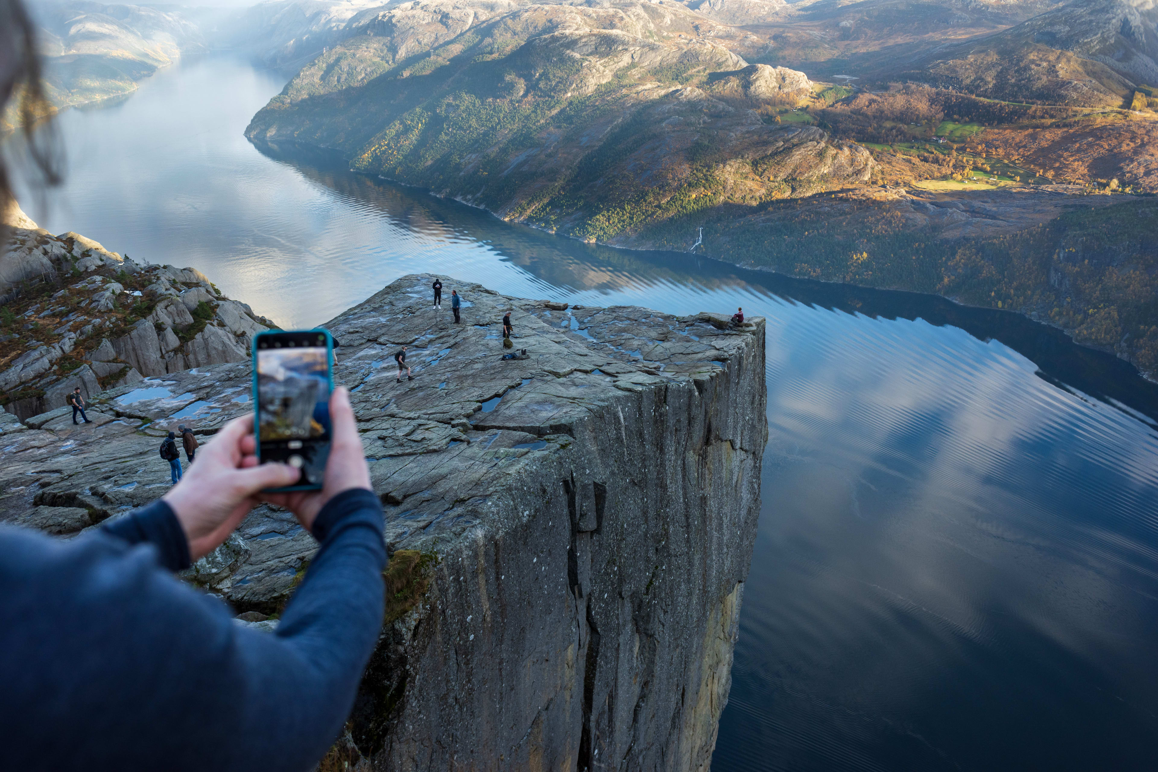 Person fotografiert den Preikestolen im Herbst