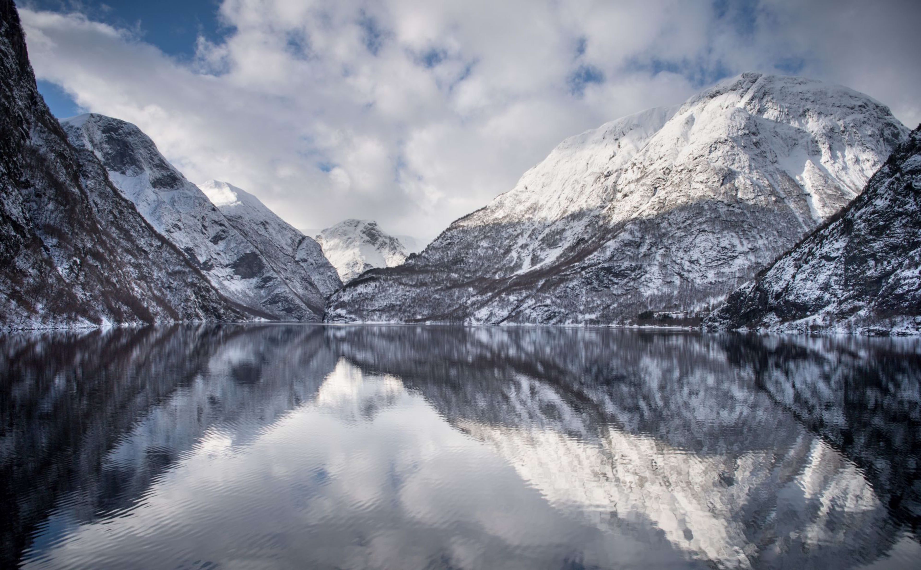 Snøkledde fjell speiler seg i rolige Nærøyfjorden, vinter Norge