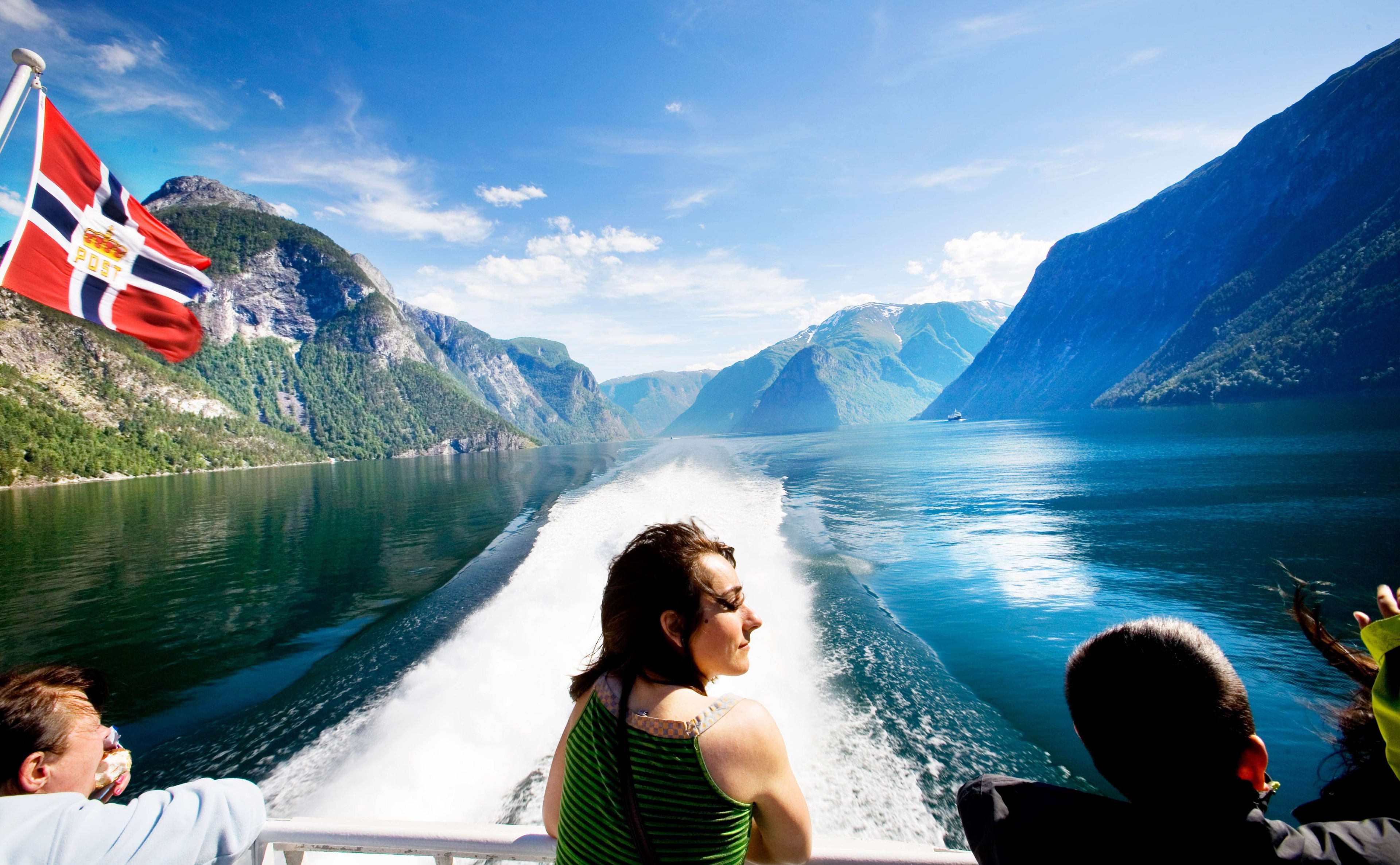 Boot am Sognefjord mit wehender Flagge und Kielwasser.