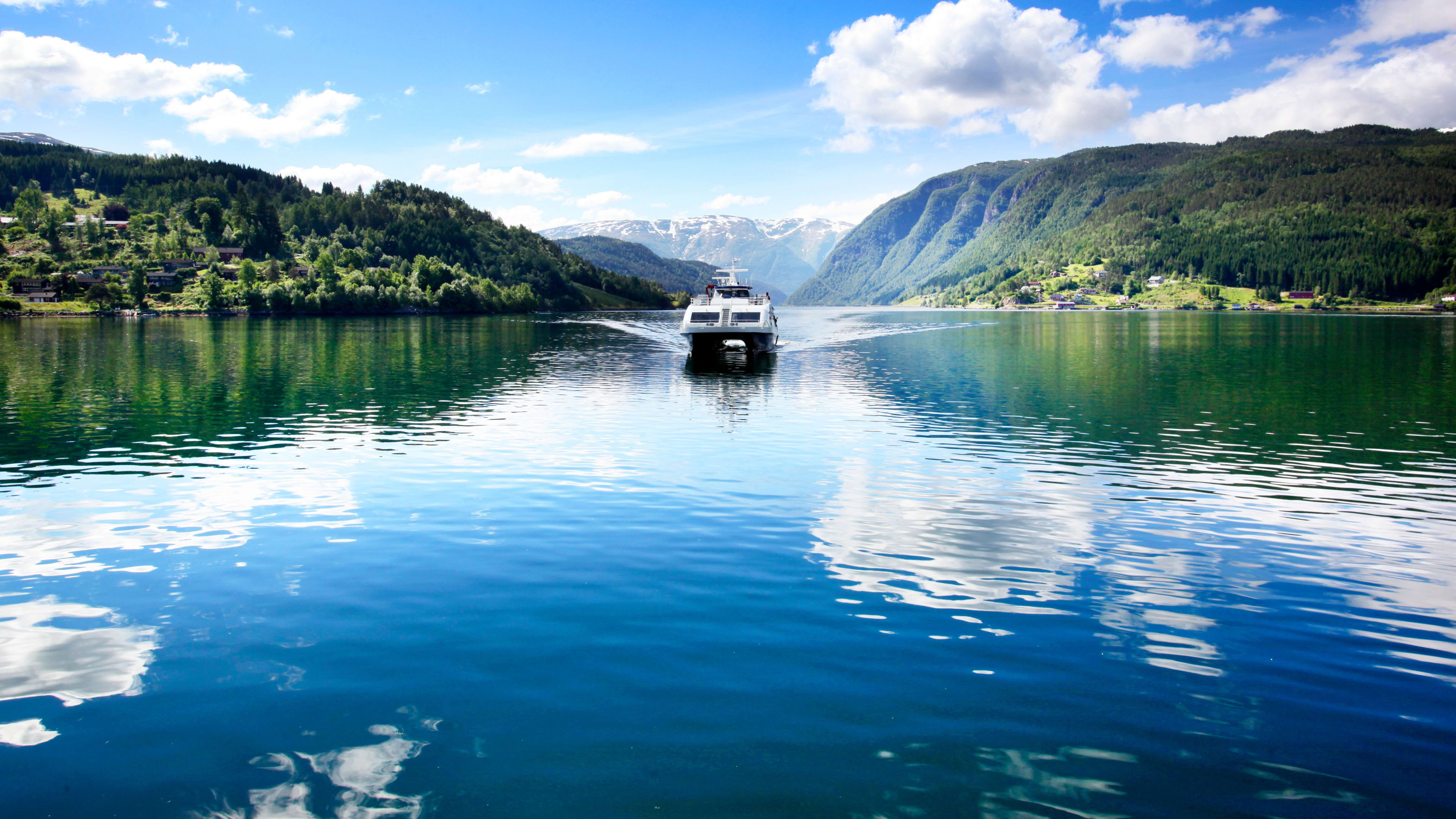 Ekspressbåten seiler på den krystallklare Hardangerfjorden en solrik sommerdag