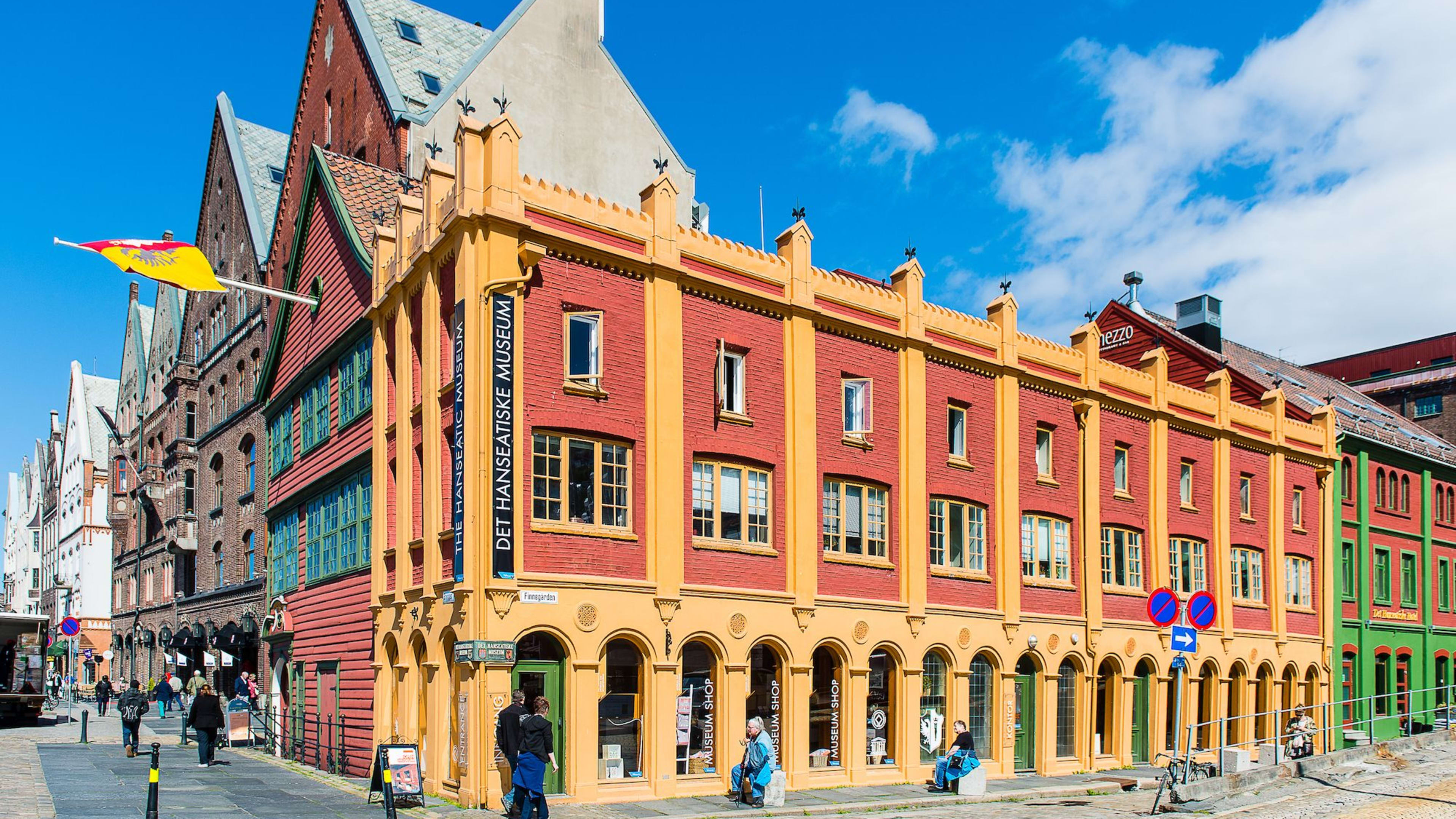 Fargerik gate med rødt og gult Hanseatisk museum, turister og tradisjonelle trehus.