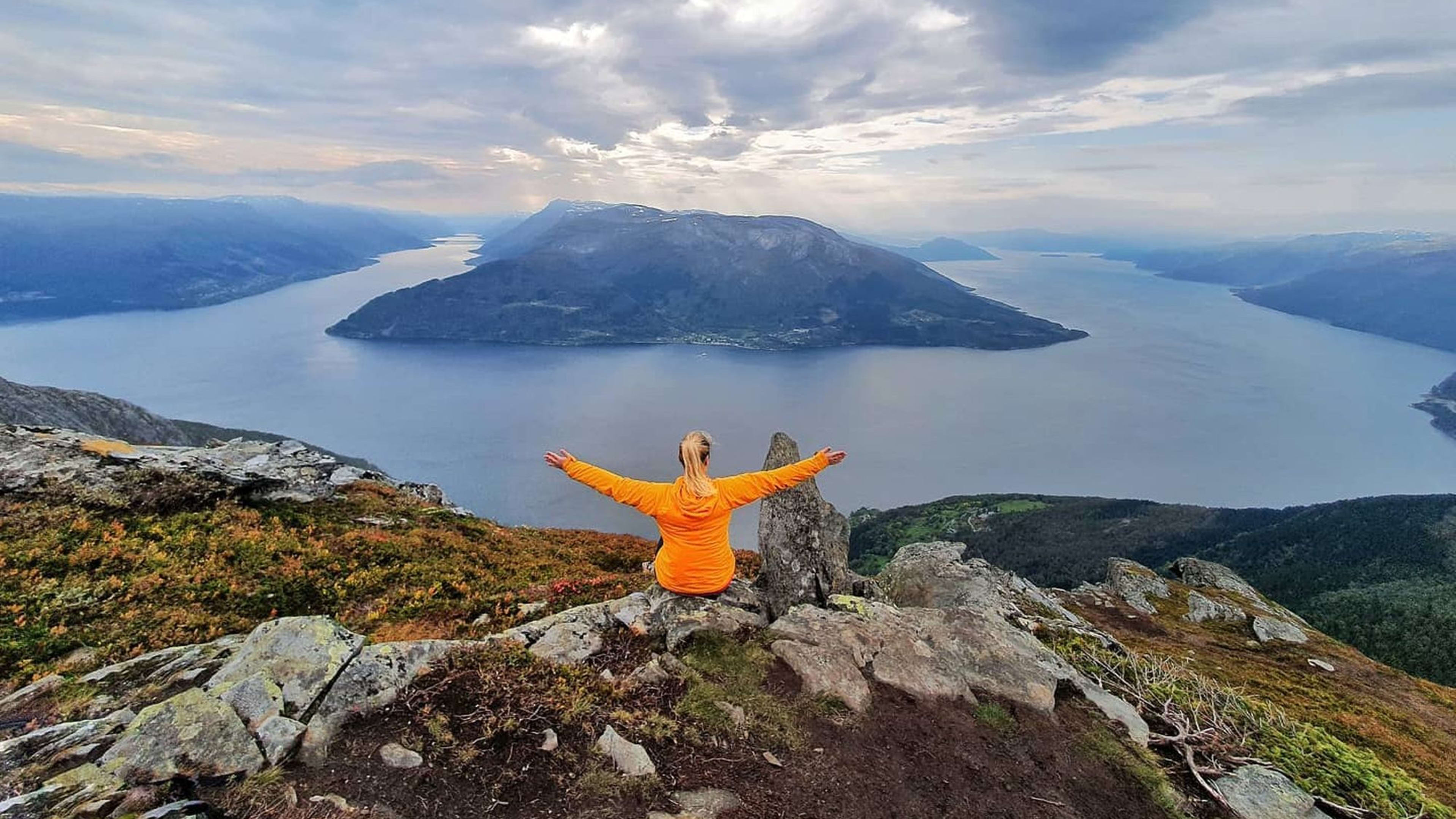 Person mit offenen Armen auf Berg über Hardangerfjord.