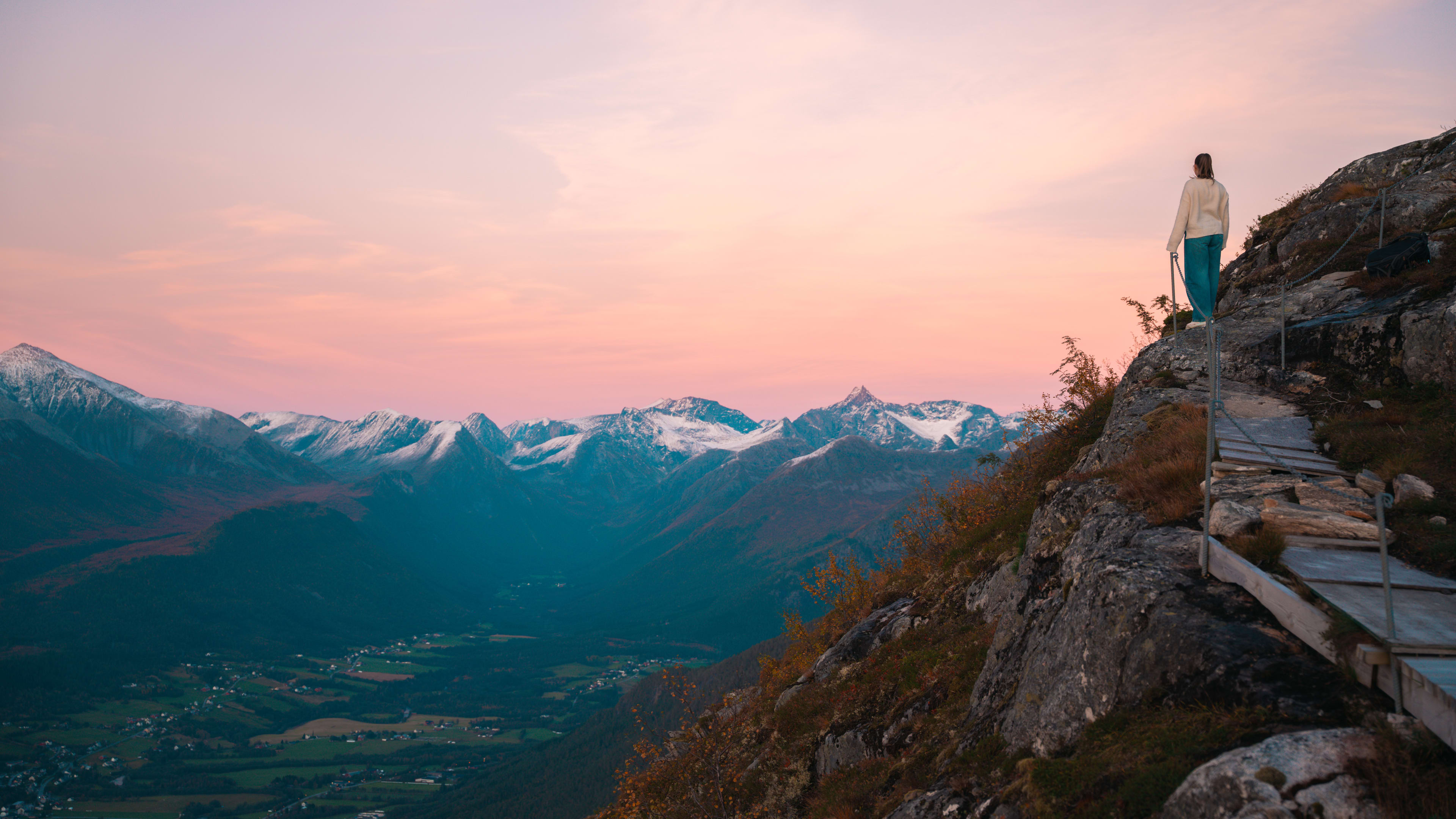 Jente som nyter solnedgang på Nesaksla i Åndalsnes med snødekte fjelltopper og rosa himmel