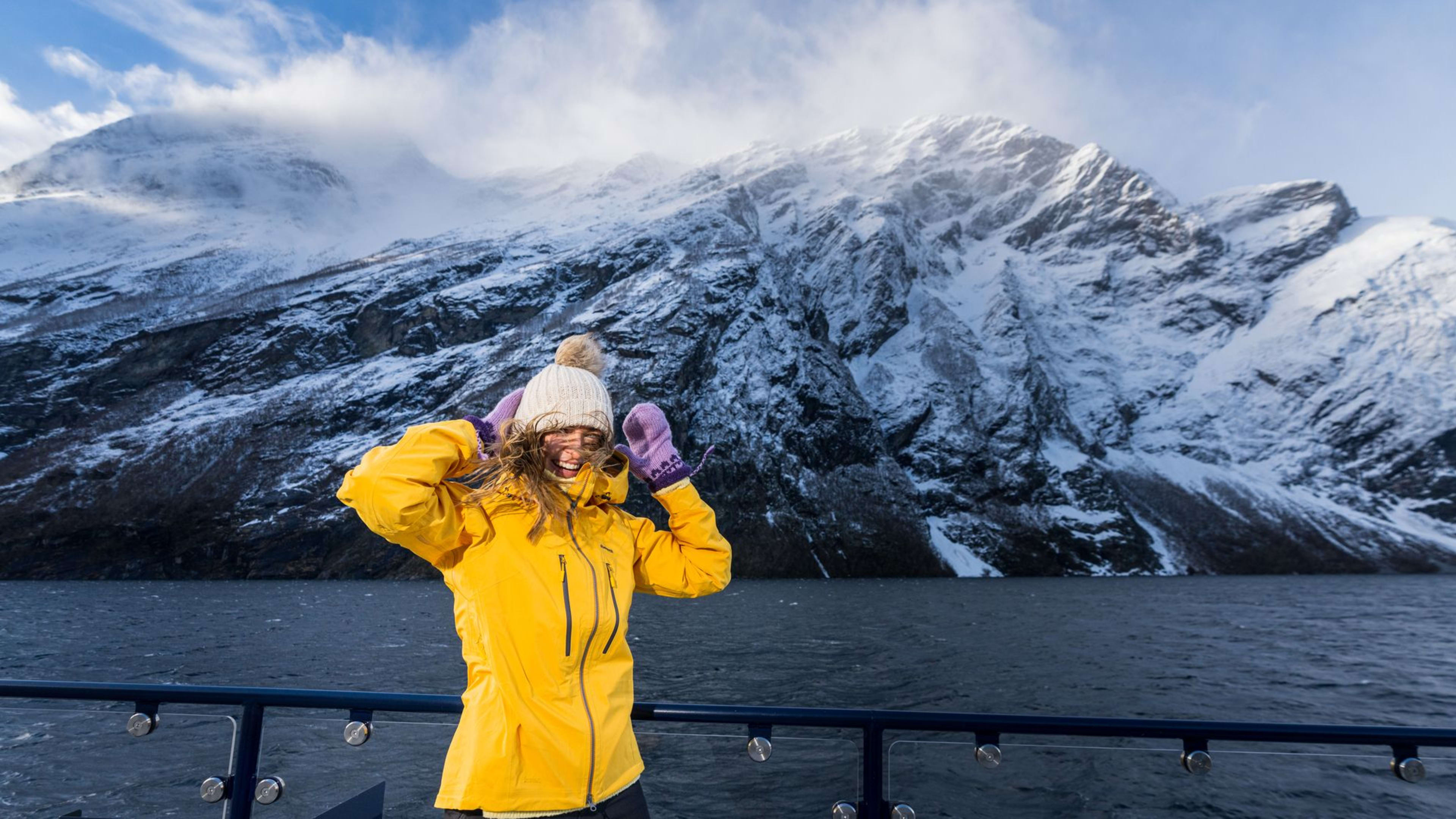 Person på Geirangerfjord vinter-cruise nyter gyllent lys over snødekt fjordlandskap