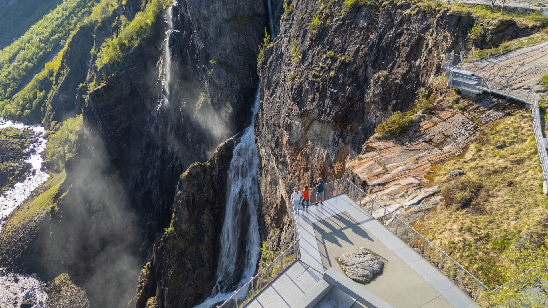 Luftfoto fra drone som viser besøkende ved Vøringfossen utsiktspunkt med utsikt over det kraftige fallet som styrter ned i Måbødalen under