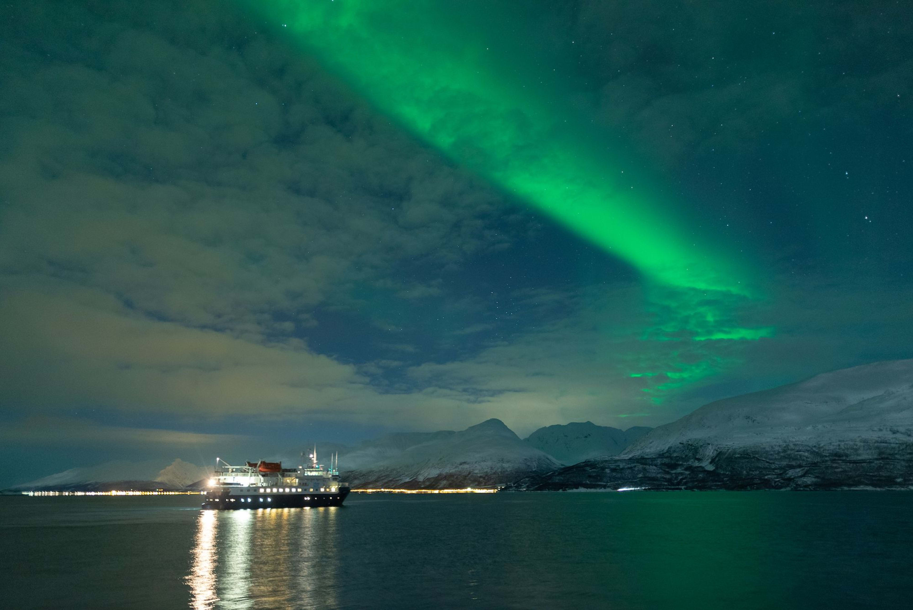 Et skip under nordlyset, flytende på rolige arktiske farvann.