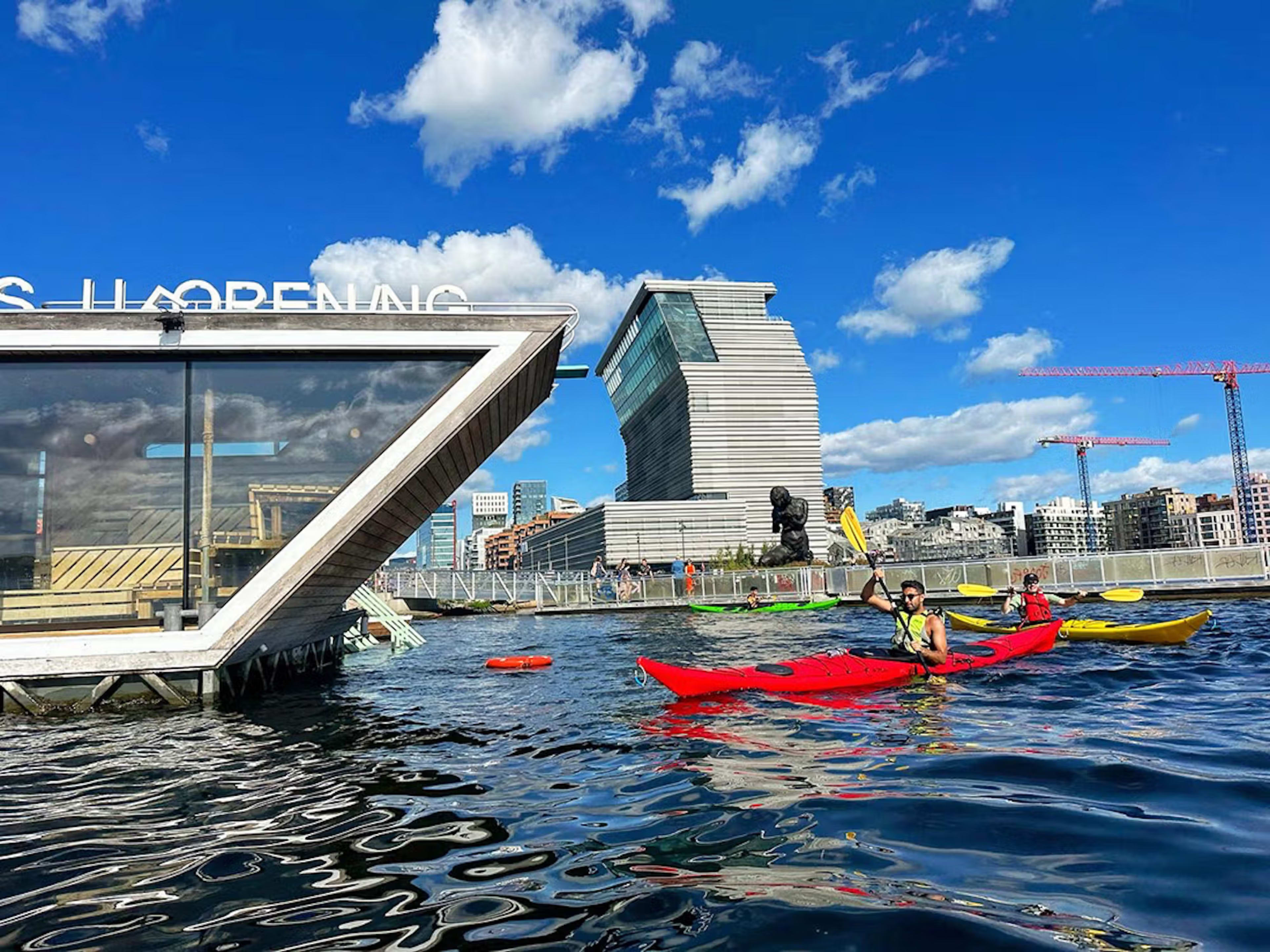 Kajakfahrer nahe schwimmender Sauna mit Munch-Museum im Hintergrund Oslo