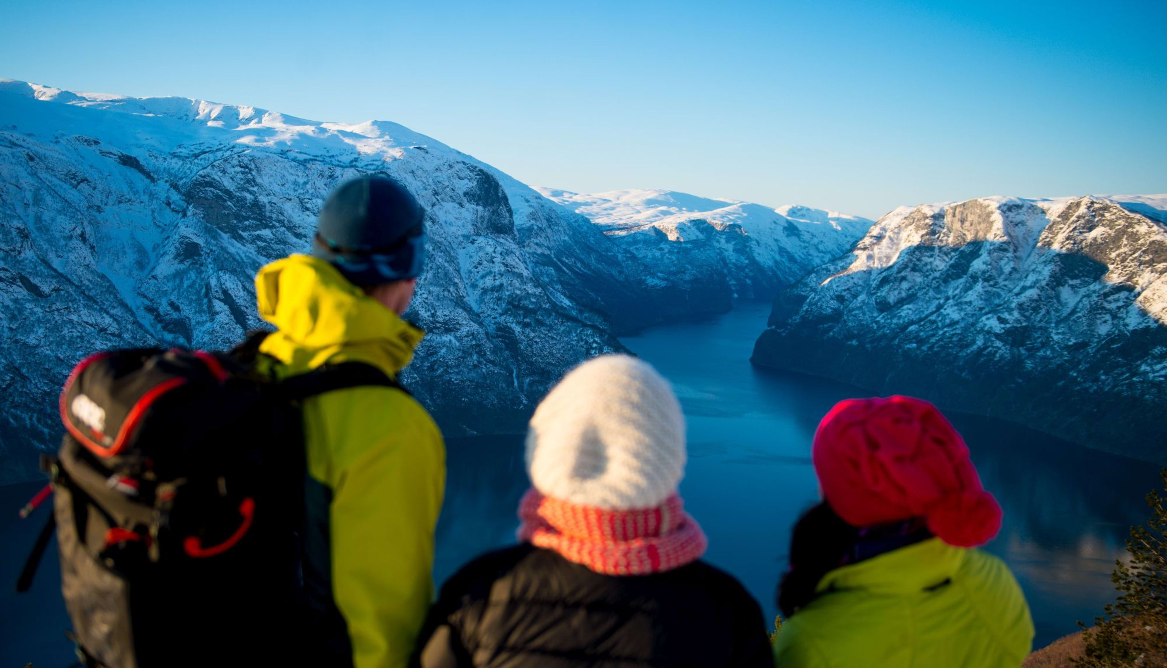 Wanderer bewundern Fjord und verschneite Berge.