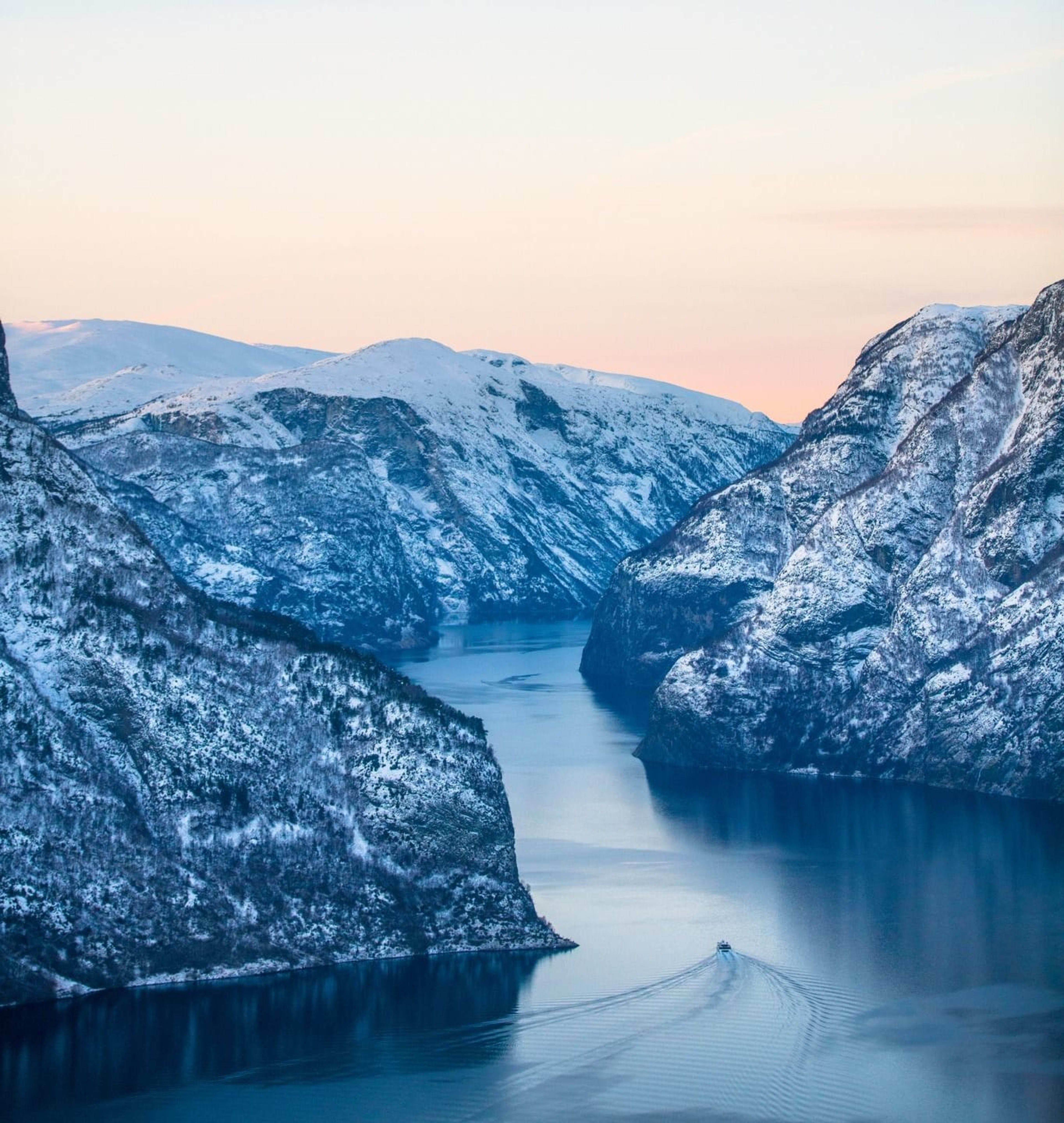 Winterabend am Aurlandsfjord - Vogelperspektive von Fjordboot mit verschneiten Bergen im goldenen Licht