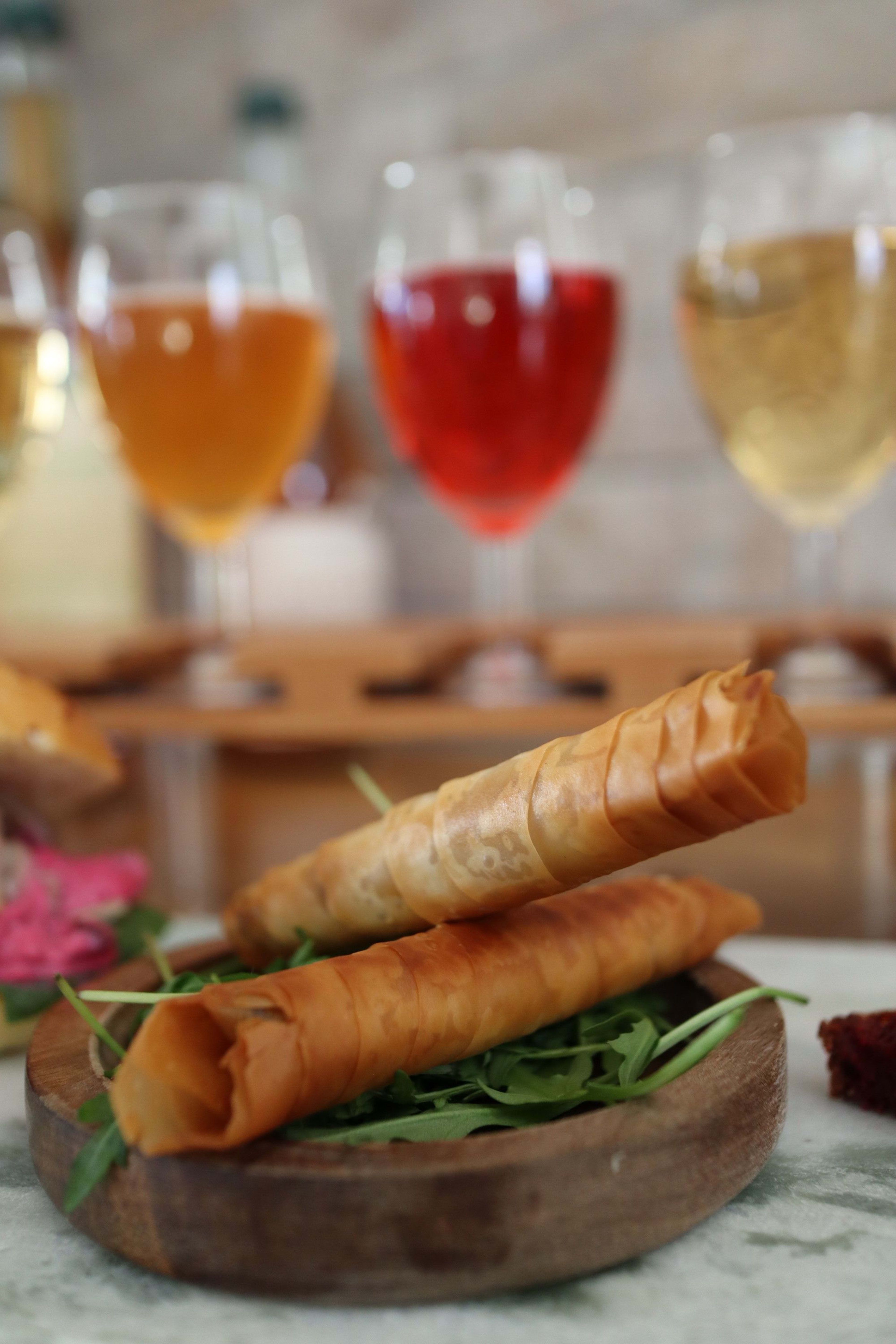 Golden pastry rolls elegantly paired with vibrant ciders, creating a tempting gourmet tasting.