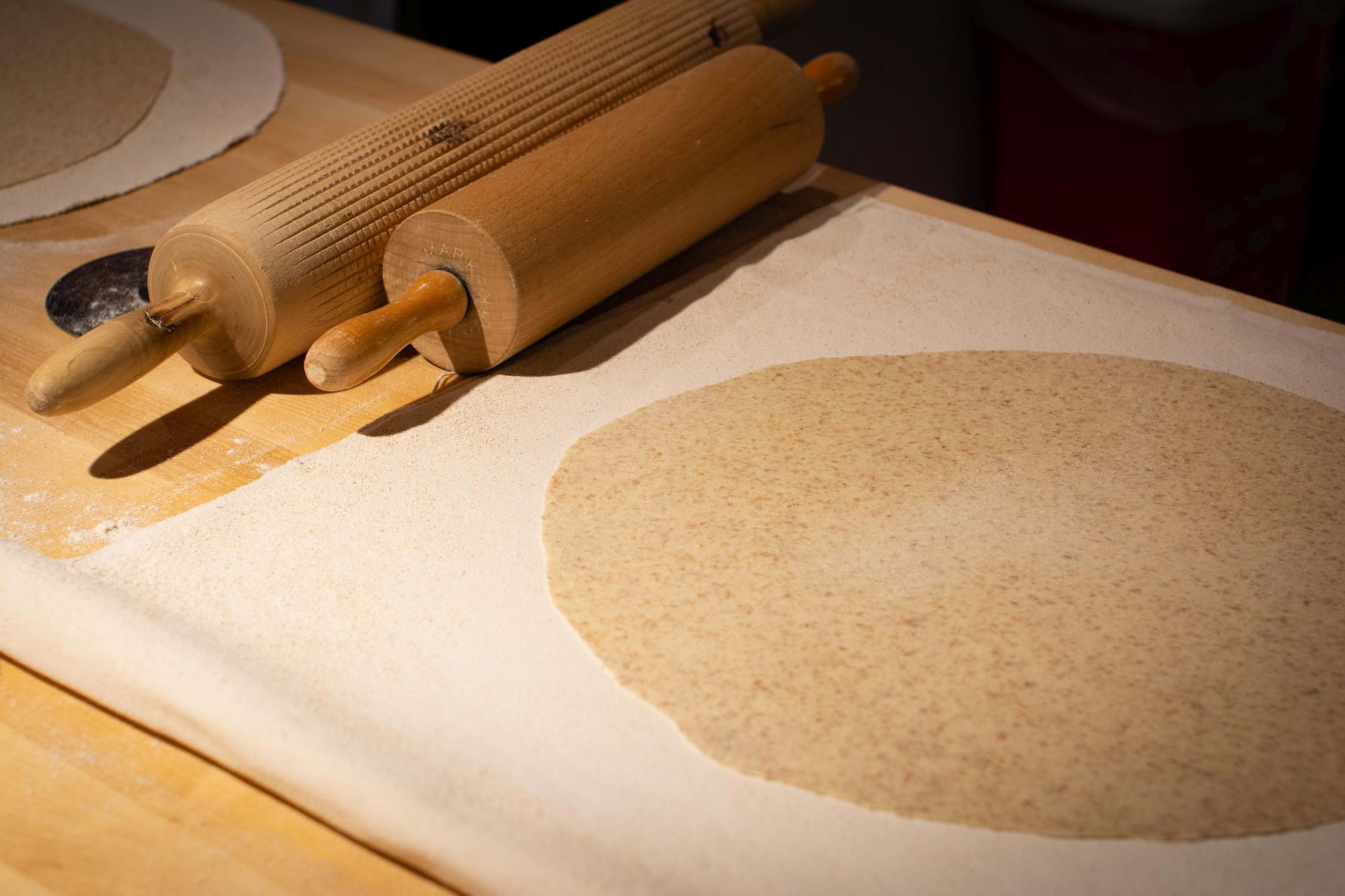 En rustikk scene med kjevler og deig som forberedes til  lefse, med mel på overflaten.