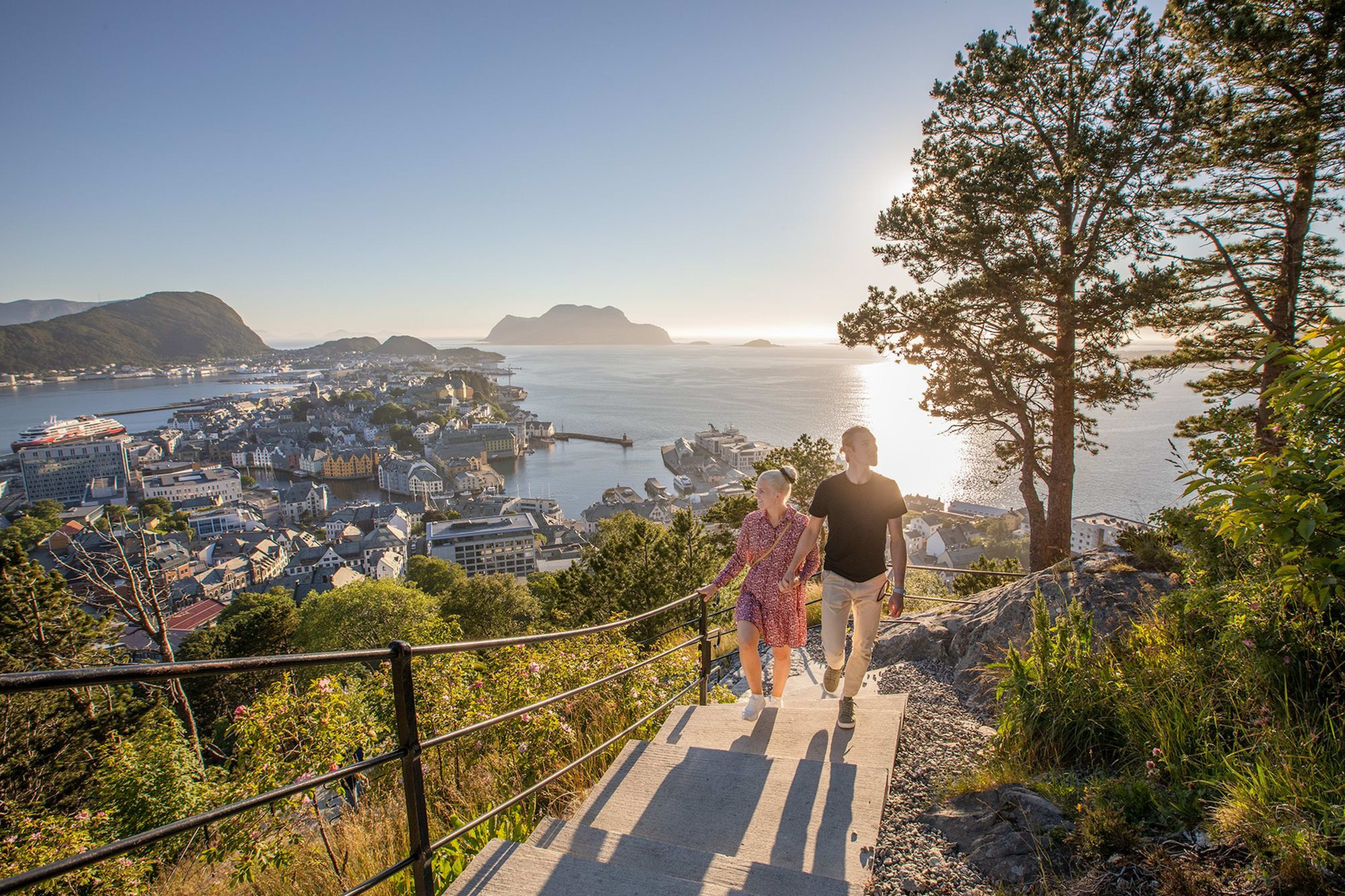Couple climbing Aksla stairs to viewpoint overlooking Art Nouveau Ålesund and surrounding fjord islands