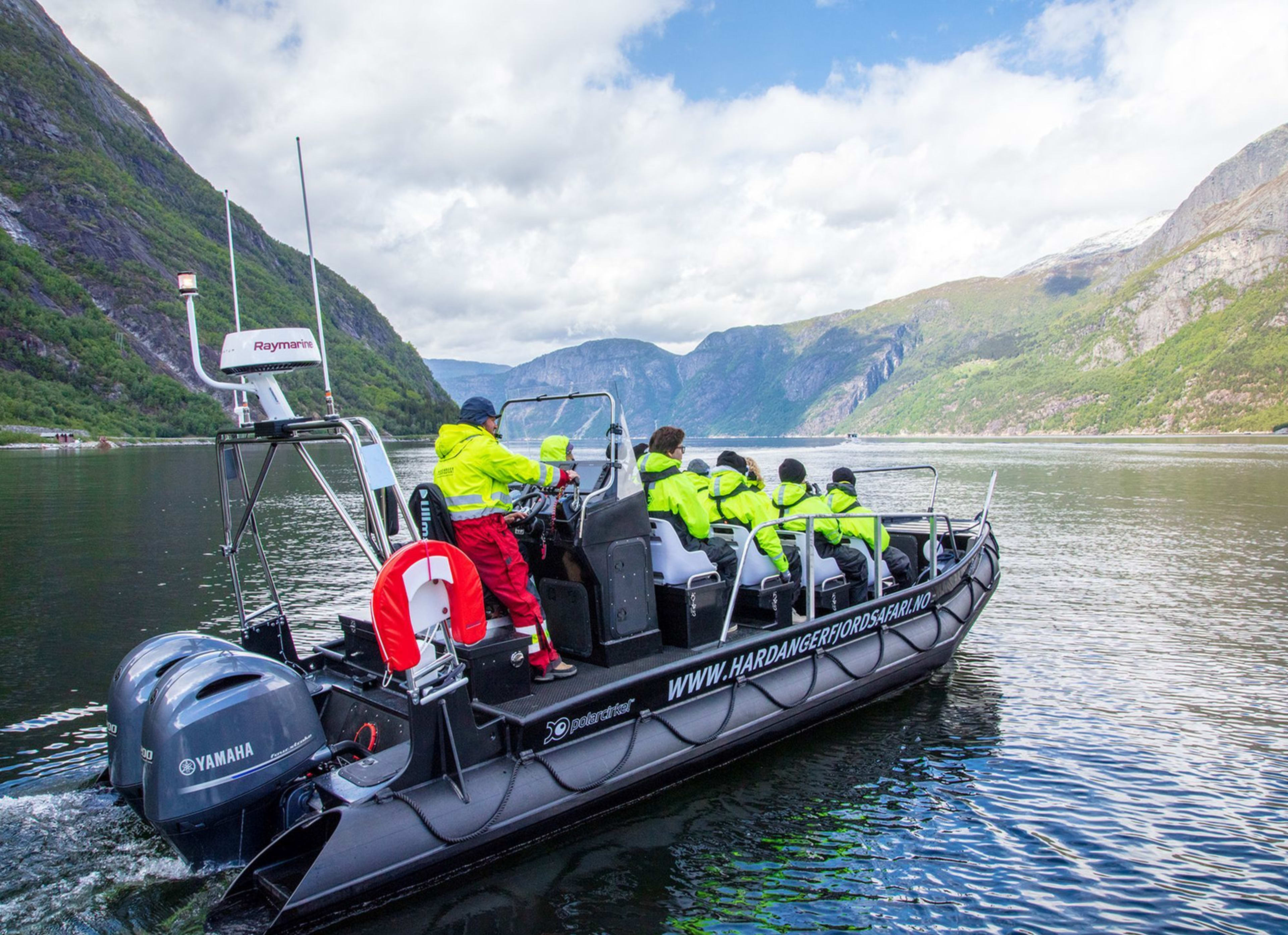 Schwarzes Boot fährt durch Fjord mit grünen Bergen.