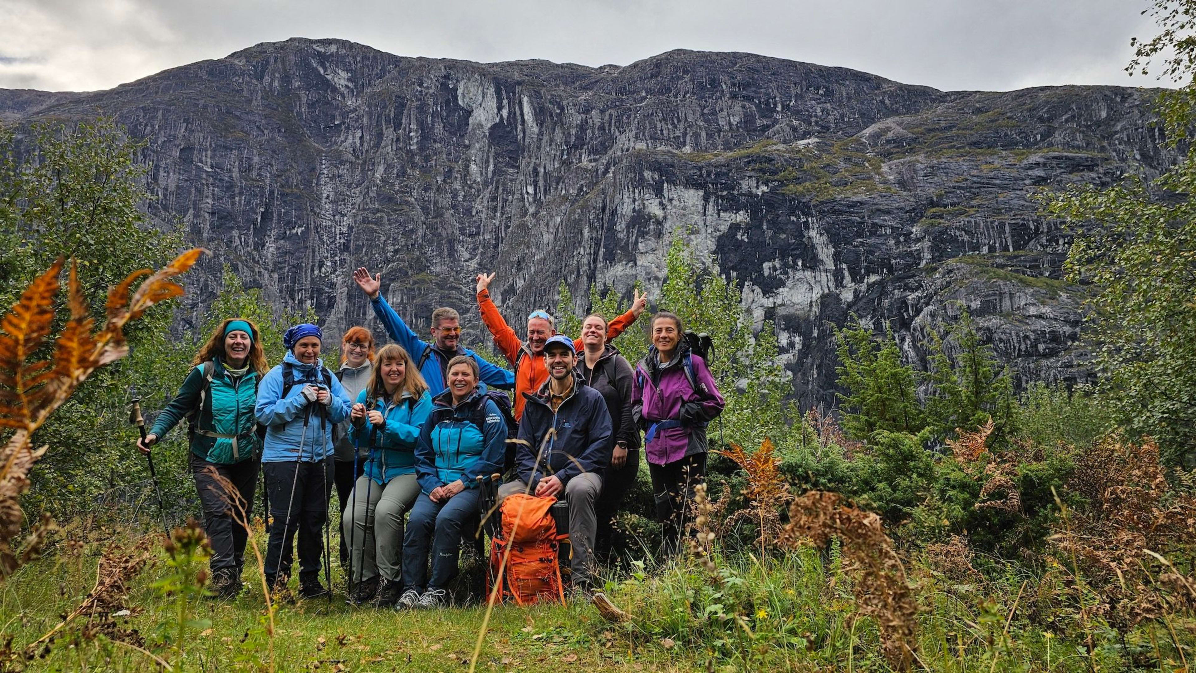 Smilende turgåere poserer med majestetiske fjell i bakgrunnen.