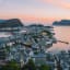 Scenic view of Ålesund, Norway, with colorful buildings, Art Nouveau architecture, and harbor under soft sunset light.