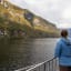 Frau genießt den Blick auf den Nærøyfjord in herbstlichen Farben während einer Fjordkreuzfahrt ab Flåm.