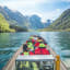 Tourists in safety jackets on RIB  boat ride through turquoise Sognefjord surrounded by lush mountains.