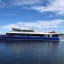 Elektrisches Boot fährt ruhig, Stadt im Hintergrund.