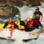 Eine Gruppe von Menschen genießt ein aufregendes Rafting-Erlebnis, paddelt durch schnell fließendes Wasser mit Wasserspritzern.