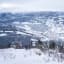 Tre går i snø over dal med fjell.
