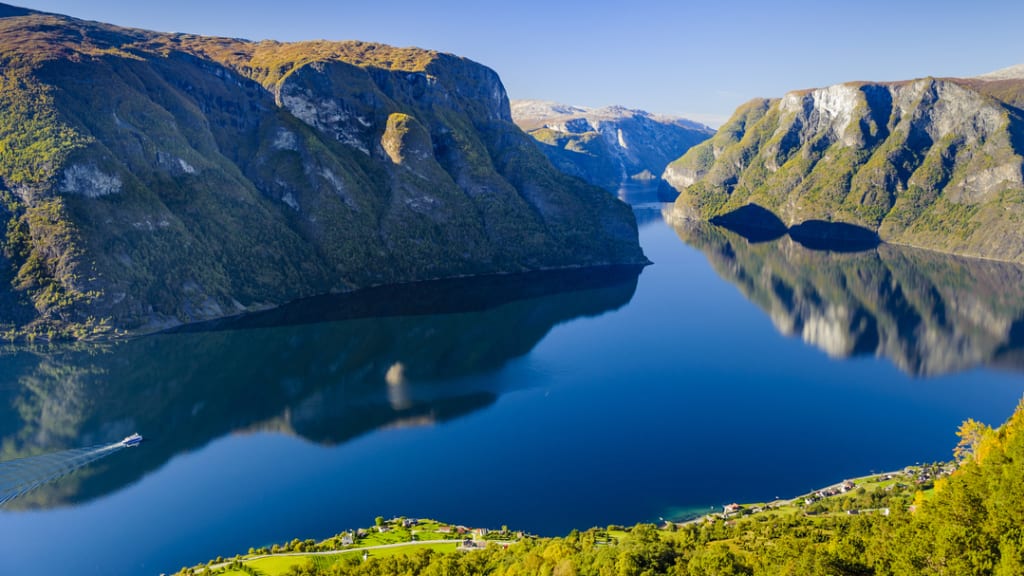 Luftfoto av Aurlandsfjorden mot Nærøyfjorden med stupbratte fjellsider og speilblankt fjordvann