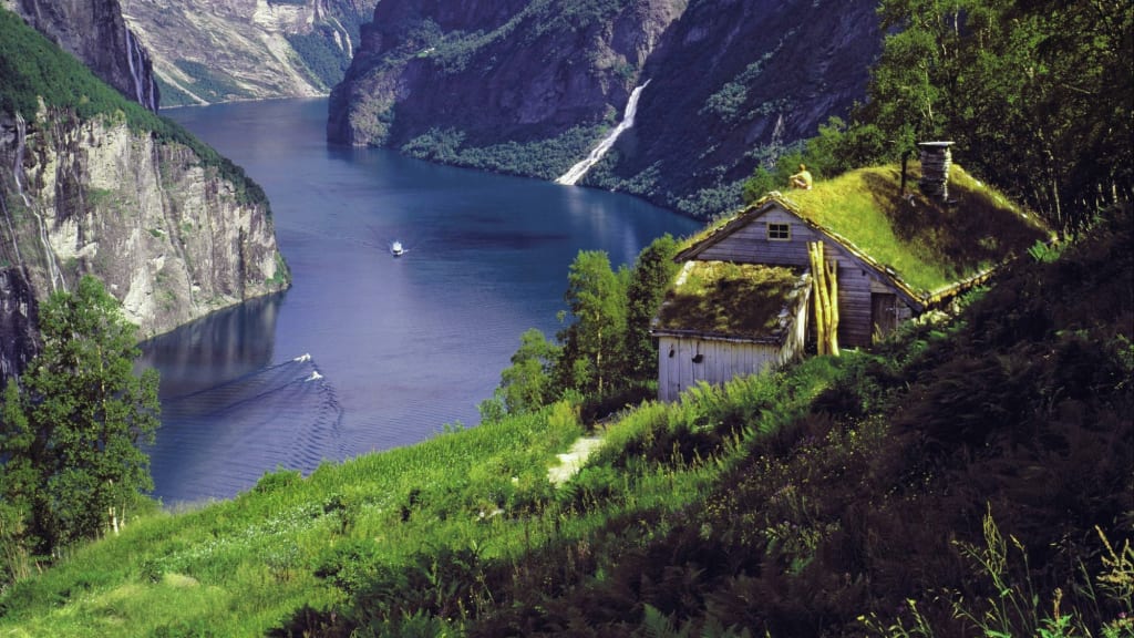 Fjord mit Wasserfällen und Grasdach-Hütte.